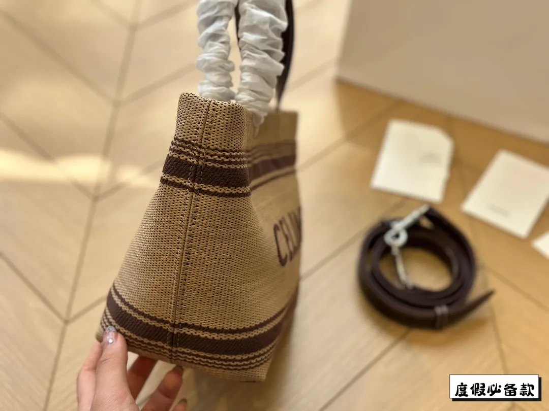 ¥220 Celine新款编织托特包 Celine新款编织包是一款设计简洁而又不失时尚感的托特包。其最显著的特点在于采用了棕色粗细不均条纹的帆布材质,这种设计不仅赋予了包包独特的视觉冲击力,也展现了Celine品牌一贯的优雅与精致。在包的正面醒目地印有大写的“CELINE”字样,既凸显了品牌的身份,也提升了包包的整体美感。20*17