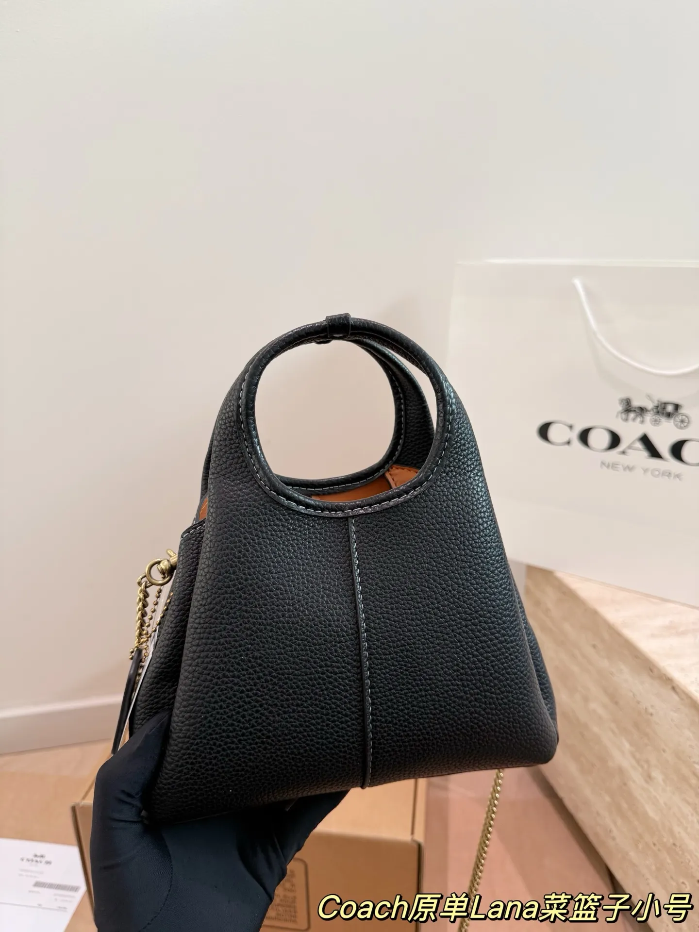 P165 COACH LANA 23号单肩包​​ 👜COACH LANA 23号单肩包，荔枝纹头层牛皮，手感柔软耐用，浅灰调超百搭，通勤休闲都能轻松驾驭✨。小巧尺寸，手提斜挎随心切换，内部隔层方便收纳手机、钥匙、口红等日常小物。金色C字Logo点缀，低调又有辨识度，简约优雅风格，秋冬大衣、针织衫都能轻松搭配，实用又时髦！ 尺寸16cm