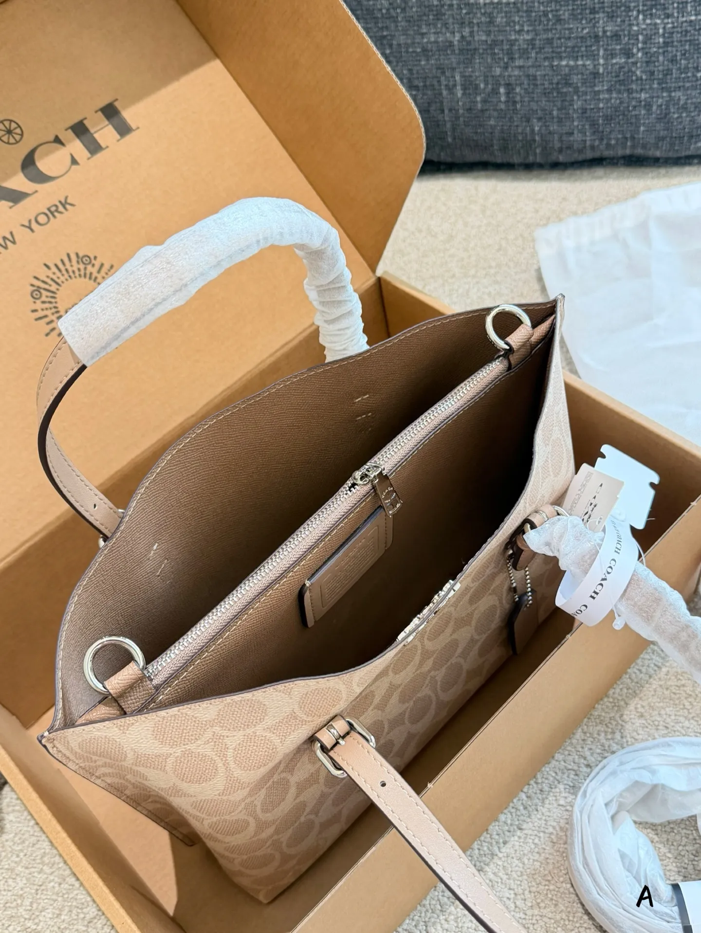 p170 Coach Mollie 25奶茶色托特包​​ 👜Coach Mollie 25奶茶色托特包，经典老花PVC材质+棕色皮革饰边，简约又耐用！25cm小巧尺寸，容量超能装，通勤日常都OK✨。手提、斜挎、单肩多种背法，肩带还能随心换，搭配超灵活～奶茶色温柔百搭，四季都能轻松驾驭，是实用又时髦的通勤神器！