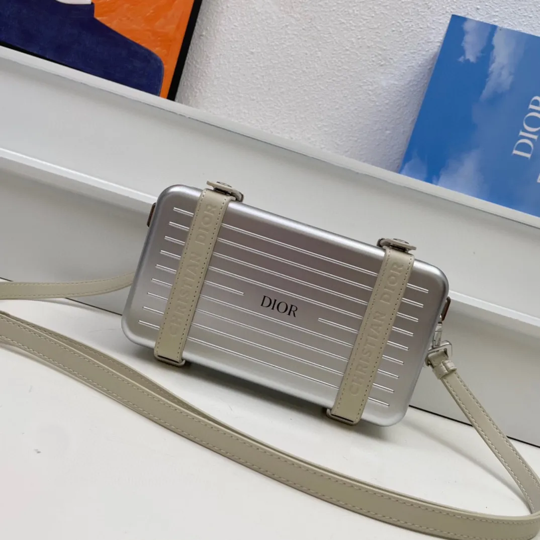 💰230包邮‼️DIOᖇ🎉🎉 (配全套包装) RIMOWA 联名限定款小行李箱子包来啦！自从Rimow&alpha;被巨头收购，感觉档次又提高了一个度，尤其是实物小盒子采用了RIMOWA标志性的磨砂质感的铝制凹槽设计 搭配oblique图案。实物细节设计更高级得没话说，尤其是外壳！有三个隔层，一个拉链零钱袋，还有6个卡位，可以放大手机，看起来不大容量却很足呀，斜挎和手拿都很OK～ 联名款的包设计风格很独特，男生背超级带感，女生背也很帅！ A926# 13.5x20x6.5cm