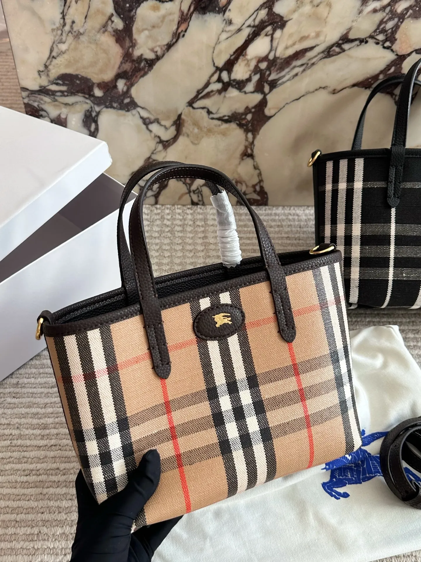p190 双面tote Burberry家最新格纹迷你托特包,选用棉质帆布面料打造,格子面料搭配光滑皮革顶部提柄,有可调式斜背带。 顶部皮革提柄 可调式网纹肩背带开放式包口设计,搭配磁扣开合内侧口袋采用磁扣开合 尺寸 22 18cm 配盒