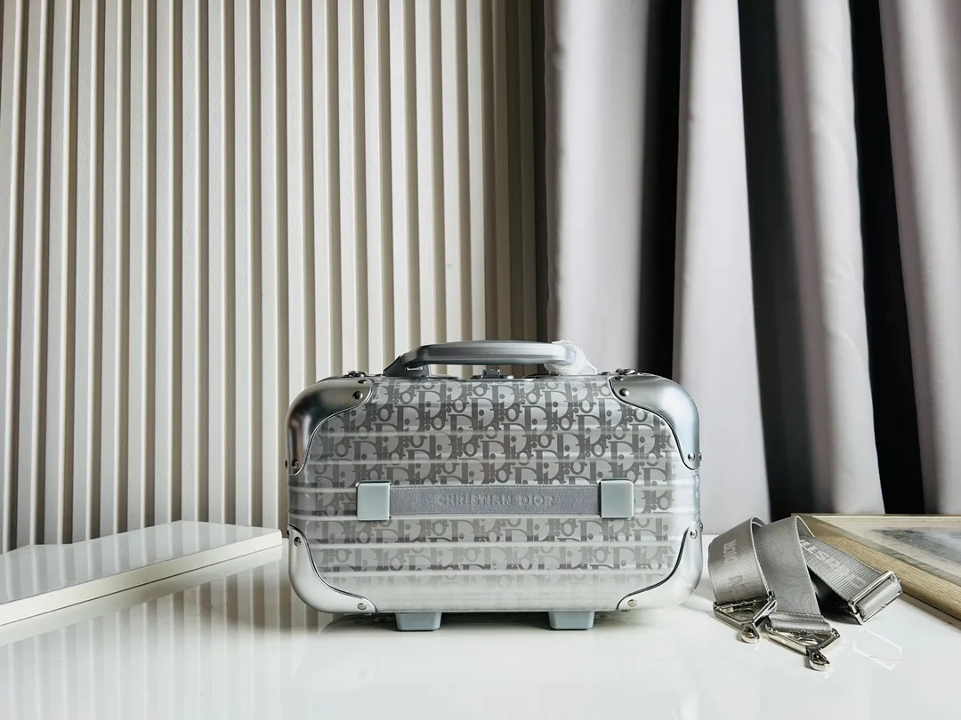 Dior联名日默瓦rimowa手提箱14寸随身登机 38cm 本季推出的 Dior & Rimowa@38 厘米手提化妆箱，可可单肩/可斜挎；选用 Damier Graphite 帆布内里，印有男装艺术总监 Virgil Abloh 设计的新款彩色交织dr系列的字母。光滑外层包裹轻巧的铝制手提和高密度斜挎带，使整个手提箱高级感倍增。箱内设计精简，左右带两居室的内测，实用且不失奢华，内里还包括 1 个拉链隔层和 1 个小插袋。 详细特征 38.0 x 16.5.0 x 22.0 cm (长 x 高 x 宽) &middot;随身上机行李尺寸 . 单肩/斜挎 ．Damier Graphite涂层定制帆布 ．两居室内衬 ．牛皮饰边 ．铝制饰件 ． ．箱内人性化合理设计 ．dr家专属内里隔层 ．顶部配有合金手柄 ．镁铝合金包角 ．内里拉链开合，配有tsa海关锁 ．4个小巧防滑底座