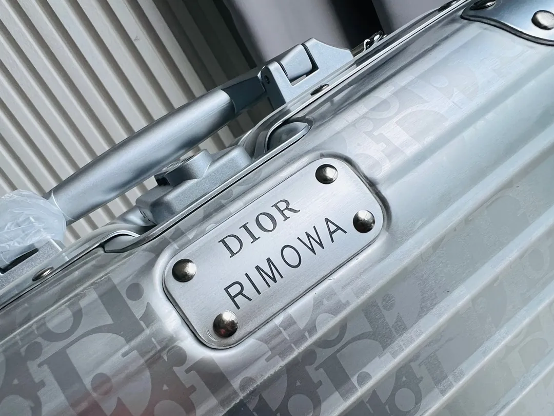 Dior联名日默瓦rimowa手提箱14寸随身登机 38cm 本季推出的 Dior & Rimowa@38 厘米手提化妆箱，可可单肩/可斜挎；选用 Damier Graphite 帆布内里，印有男装艺术总监 Virgil Abloh 设计的新款彩色交织dr系列的字母。光滑外层包裹轻巧的铝制手提和高密度斜挎带，使整个手提箱高级感倍增。箱内设计精简，左右带两居室的内测，实用且不失奢华，内里还包括 1 个拉链隔层和 1 个小插袋。 详细特征 38.0 x 16.5.0 x 22.0 cm (长 x 高 x 宽) &middot;随身上机行李尺寸 . 单肩/斜挎 ．Damier Graphite涂层定制帆布 ．两居室内衬 ．牛皮饰边 ．铝制饰件 ． ．箱内人性化合理设计 ．dr家专属内里隔层 ．顶部配有合金手柄 ．镁铝合金包角 ．内里拉链开合，配有tsa海关锁 ．4个小巧防滑底座