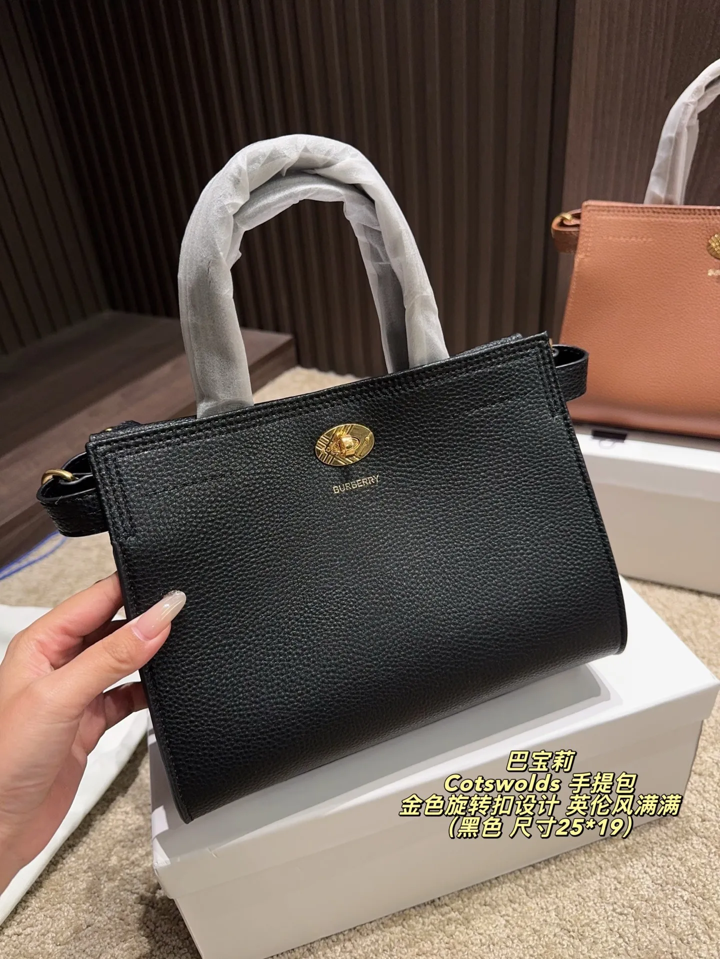 P220配盒⚠️尺寸25*19 Burberry 巴宝莉Cotswolds 手提包 采用粒面小牛皮，质感细腻耐用，低调奢华。金色旋转扣设计，英伦风满满，简约又精致。包身轻盈，容量适中，通勤或出行都很实用。内部空问合理，日常物品轻松收纳。黑色款百搭，适合多种穿搭，是实用与时尚兼具的经典之选的。