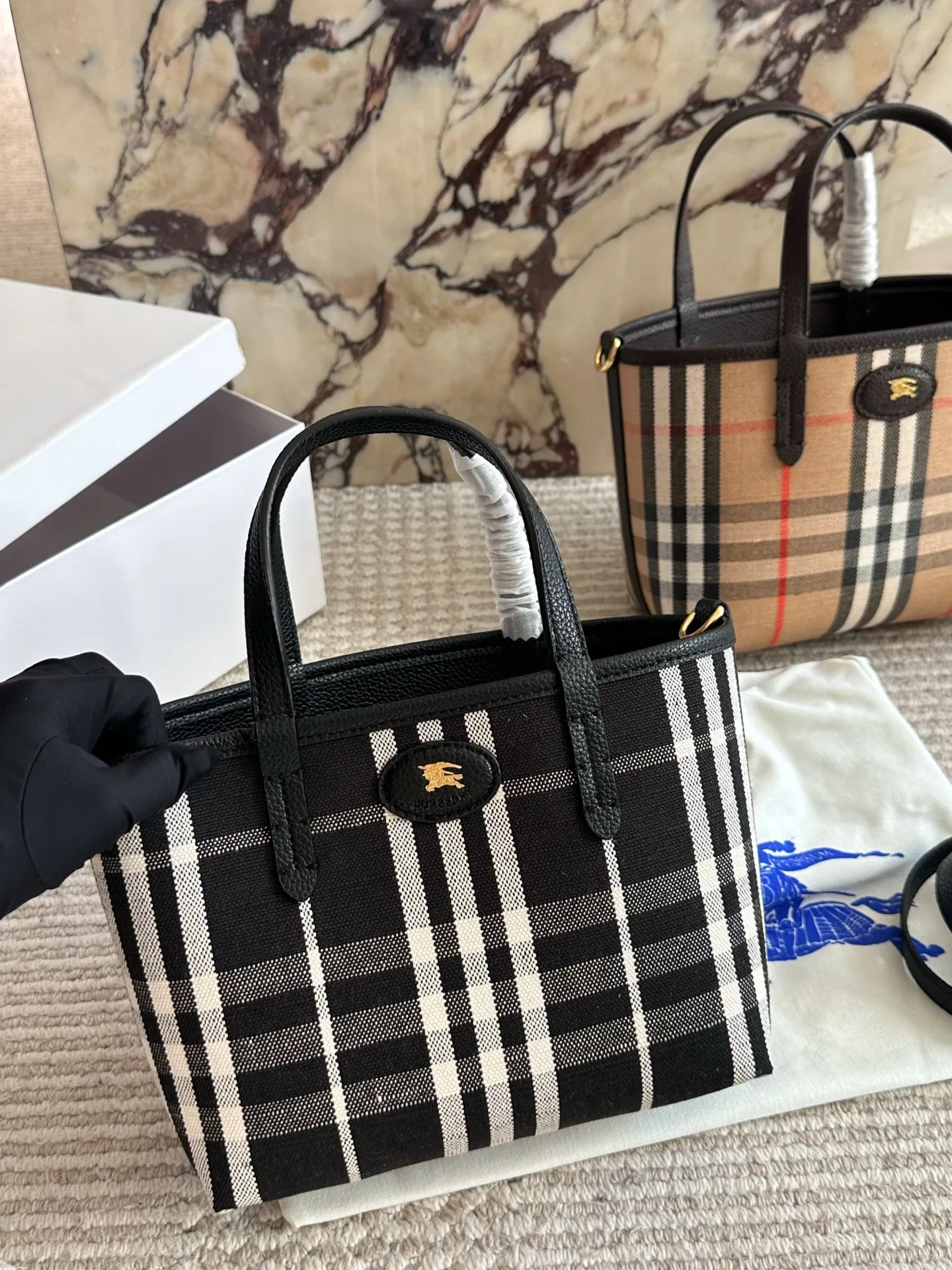 p190 双面tote Burberry家最新格纹迷你托特包,选用棉质帆布面料打造,格子面料搭配光滑皮革顶部提柄,有可调式斜背带。 顶部皮革提柄 可调式网纹肩背带开放式包口设计,搭配磁扣开合内侧口袋采用磁扣开合 尺寸 22 18cm 配盒