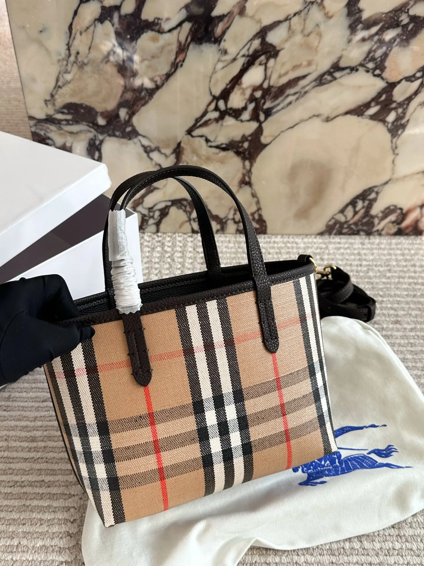 p190 双面tote Burberry家最新格纹迷你托特包,选用棉质帆布面料打造,格子面料搭配光滑皮革顶部提柄,有可调式斜背带。 顶部皮革提柄 可调式网纹肩背带开放式包口设计,搭配磁扣开合内侧口袋采用磁扣开合 尺寸 22 18cm 配盒