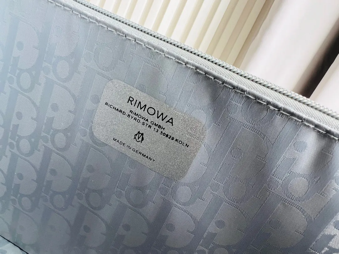 Dior联名日默瓦rimowa手提箱14寸随身登机 38cm 本季推出的 Dior & Rimowa@38 厘米手提化妆箱，可可单肩/可斜挎；选用 Damier Graphite 帆布内里，印有男装艺术总监 Virgil Abloh 设计的新款彩色交织dr系列的字母。光滑外层包裹轻巧的铝制手提和高密度斜挎带，使整个手提箱高级感倍增。箱内设计精简，左右带两居室的内测，实用且不失奢华，内里还包括 1 个拉链隔层和 1 个小插袋。 详细特征 38.0 x 16.5.0 x 22.0 cm (长 x 高 x 宽) &middot;随身上机行李尺寸 . 单肩/斜挎 ．Damier Graphite涂层定制帆布 ．两居室内衬 ．牛皮饰边 ．铝制饰件 ． ．箱内人性化合理设计 ．dr家专属内里隔层 ．顶部配有合金手柄 ．镁铝合金包角 ．内里拉链开合，配有tsa海关锁 ．4个小巧防滑底座