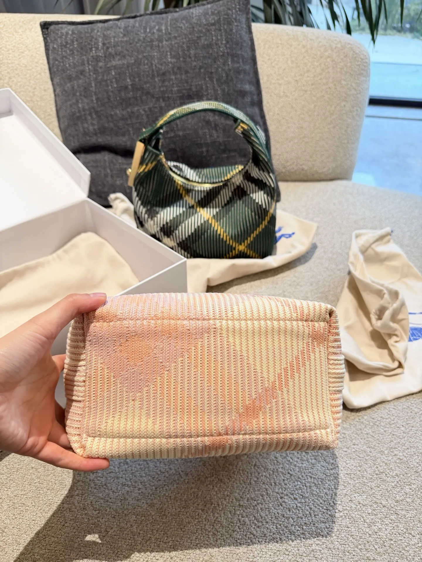 p215 Burberry粉色Peg腋下包 Burberry粉色Peg腋下包，采用柔软编织材质,触感温暖轻盈，春夏穿搭超适合!包身简约，经典格纹+蜜桃粉，清新优雅又百搭+。23x10.5x21.5cm约23x10.5x21.5cm，容量适中，通勤休闲都能hold住。双提手设计，手提肩背都OK，实用又时髦。Peg系列是Burberry经典款，时尚圈超受欢迎，春夏裙装或休闲装都能轻松搭配，日常出街必备!