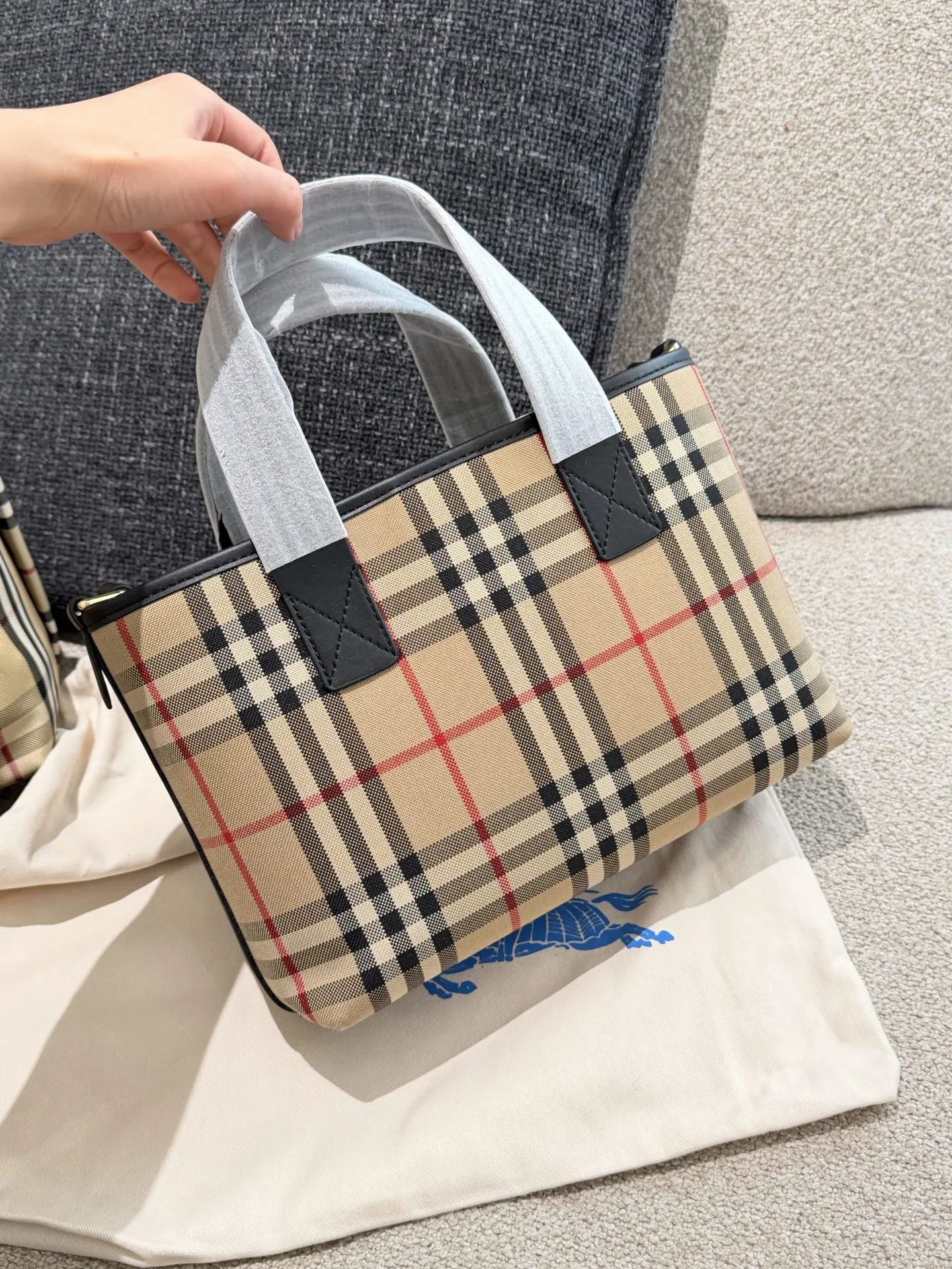 p150 Burberry家最新格纹迷你托特包，选用棉质帆布面料打造，格子面料搭配光滑皮革顶部提柄，有可调式斜背带。 顶部皮革提柄 可调式网纹肩背带开放式包口设计，搭配磁扣开合内侧口袋采用磁扣开合 尺寸 27/16.5/10