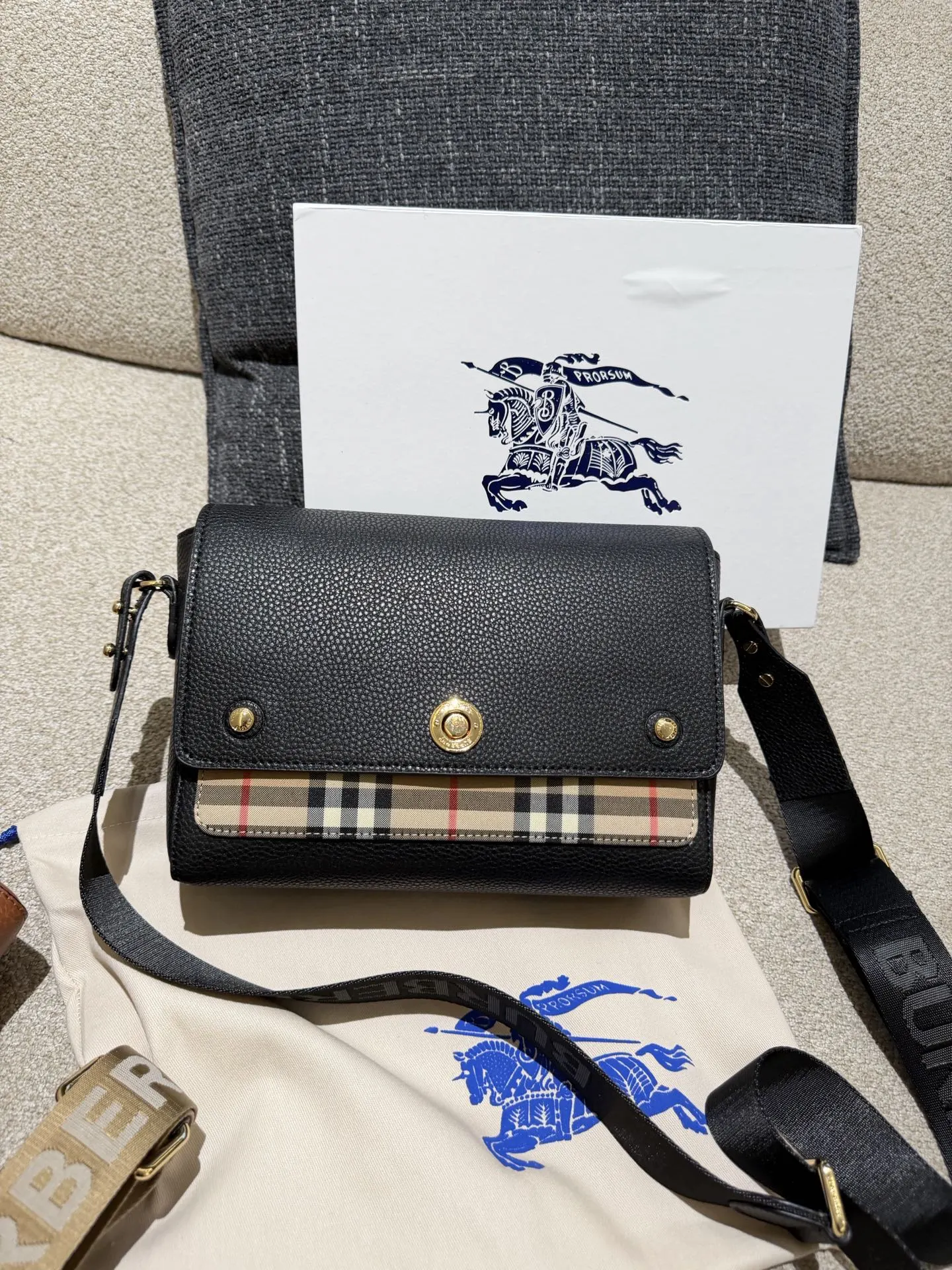 Burberry Note邮差包p165 Burberry Note邮差包,荔枝纹牛皮+经典格纹拼接,低 调又高级!25x17x8cm25x17x8cm,容量超能装,iPad、 雨伞都能放,通勤日常都OK++。宽肩带可调节,减压又百搭,休闲西装都能配。包盖吸扣设计,开合方便,内部空间合理,实用性满分!荔枝纹耐磨耐用,日常通勤、旅行都很 适合,是Burberry经典款,真的很推荐入手!