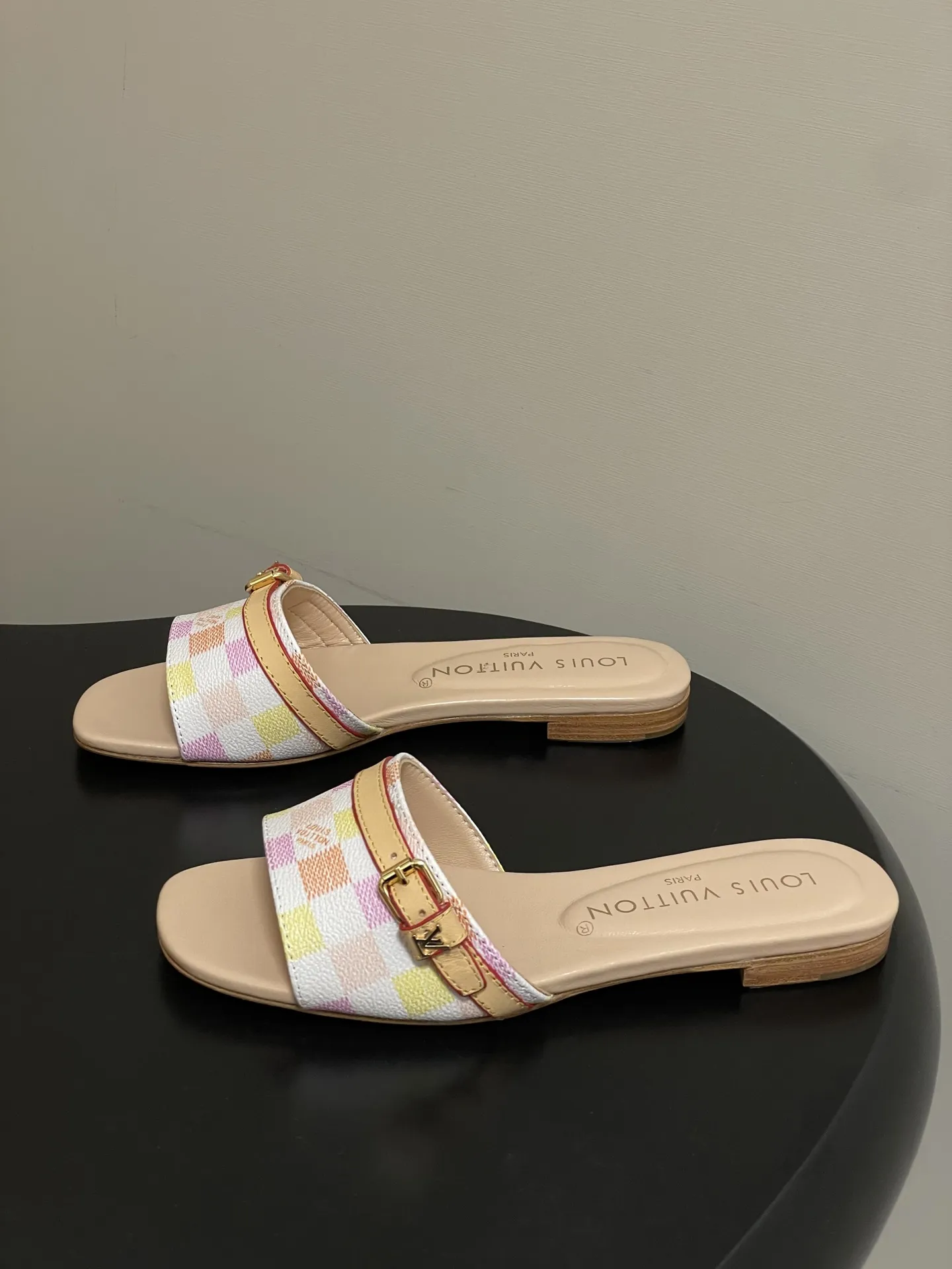 p260- 25ss夏季新款 LOUIS VUITTON 路易威登 Lv L经典棋盘格平底一字带凉拖鞋 采用经典的棋盘格图案设计，由粉色、黄色、白色等多种柔和色调组成，色彩搭配清新且富有层次感，视觉上给人活泼俏皮的感觉。同时，棋盘格作为LV的标志性元素之一，彰显品牌独特风格与辨识度。 鞋面上有一条皮质鞋带，增加了鞋子的层次感和可调节性。鞋带两端配有金属扣装饰，精致的金属配件不仅提升了鞋子的质感，还为整体造型增添了一丝时尚感和精致感。 鞋面：定制老花皮 内里垫脚：羊皮 鞋底：意大利加厚真皮大底 码数：35-41（40.41定做不退换）