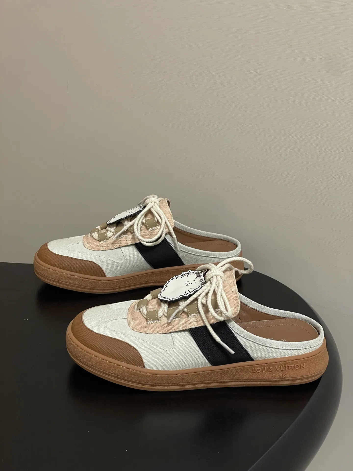 p310-（配高档飞机盒✈️） 2026春夏新款 LOUIS VUITTON 路易威登 LV Grace Coddington / 联名款猫猫Catogram系列 Lous露跟运动鞋系带包头穆勒厚底半拖鞋 LV与Grace Coddington联名的猫猫系列半拖鞋，米白+棕色拼接，麂皮和织物材质，鞋面有猫咪挂饰超可爱！ 本款Lous露跟运动鞋携Monogram压纹绒面牛皮革重回视野，为加垫鞋舌压印路易威登标识，与双鞋带一道展露滑板鞋的灵感启发。便 捷穿脱的设计升级舒适体验。 鞋面：定制布料拼接牛反绒 内里垫脚：羊皮 鞋底：开模橡胶大底 码数：女35-39（40.41定做不退换）