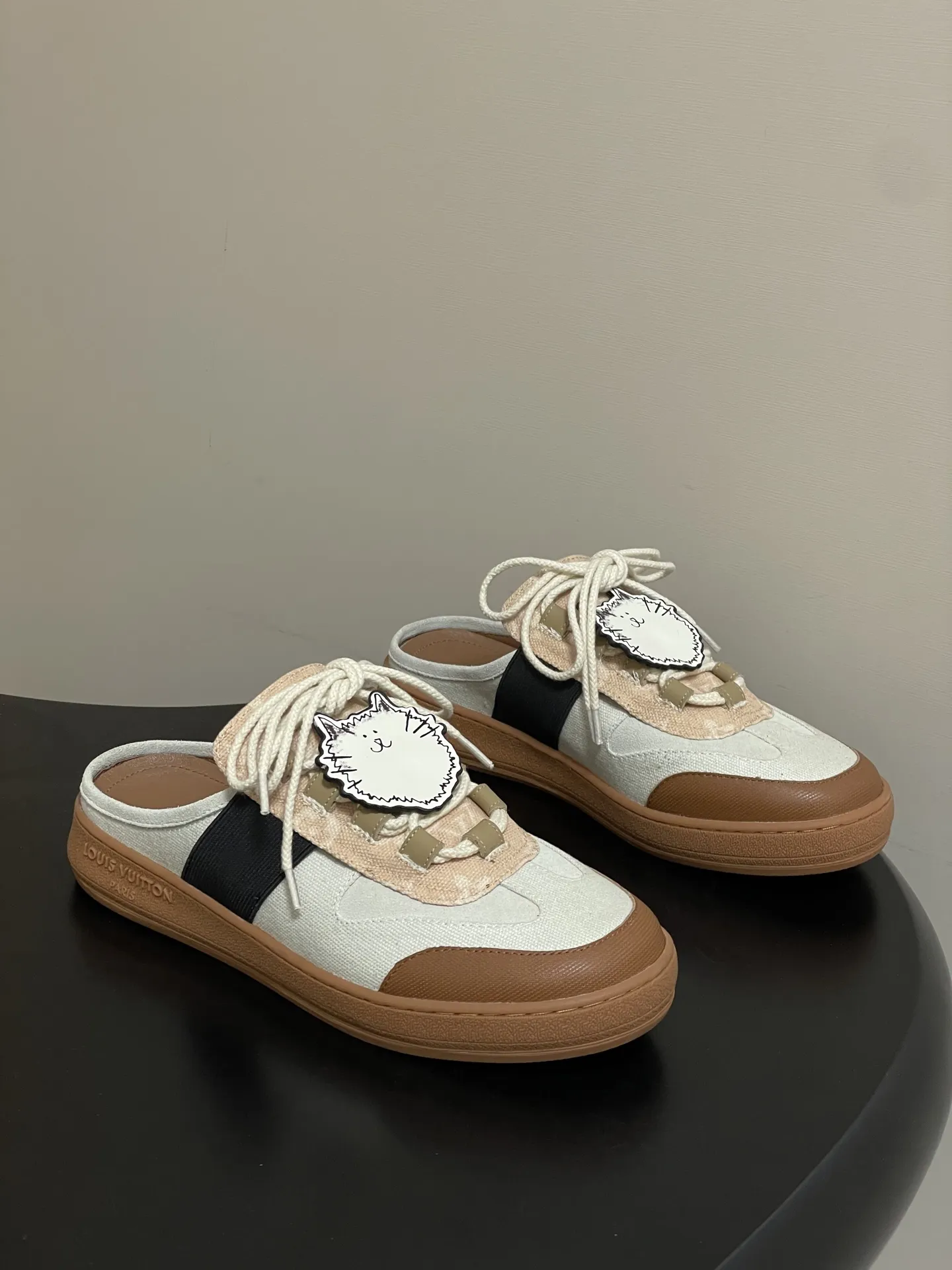 p310-(配高档飞机盒✈️) 2026春夏新款 LOUIS VUITTON 路易威登 LV Grace Coddington / 联名款猫猫Catogram系列 Lous露跟运动鞋系带包头穆勒厚底半拖鞋 LV与Grace Coddington联名的猫猫系列半拖鞋,米白+棕色拼接,麂皮和织物材质,鞋面有猫咪挂饰超可爱! 本款Lous露跟运动鞋携Monogram压纹绒面牛皮革重回视野,为加垫鞋舌压印路易威登标识,与双鞋带一道展露滑板鞋的灵感启发。便 捷穿脱的设计升级舒适体验。 鞋面:定制布料拼接牛反绒 内里垫脚:羊皮 鞋底:开模橡胶大底 码数:女35-39(40.41定做不退换)