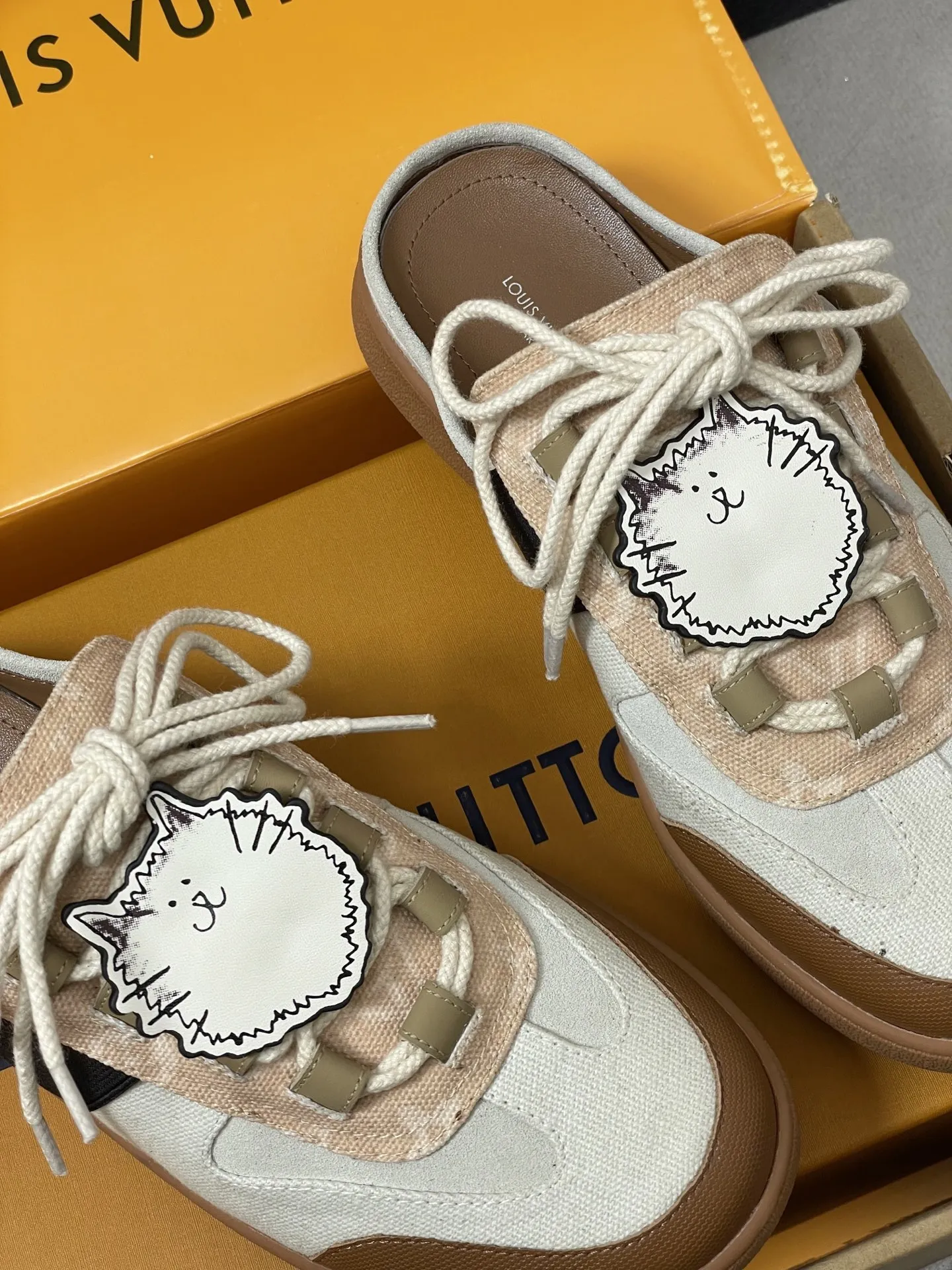 p310-（配高档飞机盒✈️） 2026春夏新款 LOUIS VUITTON 路易威登 LV Grace Coddington / 联名款猫猫Catogram系列 Lous露跟运动鞋系带包头穆勒厚底半拖鞋 LV与Grace Coddington联名的猫猫系列半拖鞋，米白+棕色拼接，麂皮和织物材质，鞋面有猫咪挂饰超可爱！ 本款Lous露跟运动鞋携Monogram压纹绒面牛皮革重回视野，为加垫鞋舌压印路易威登标识，与双鞋带一道展露滑板鞋的灵感启发。便 捷穿脱的设计升级舒适体验。 鞋面：定制布料拼接牛反绒 内里垫脚：羊皮 鞋底：开模橡胶大底 码数：女35-39（40.41定做不退换）