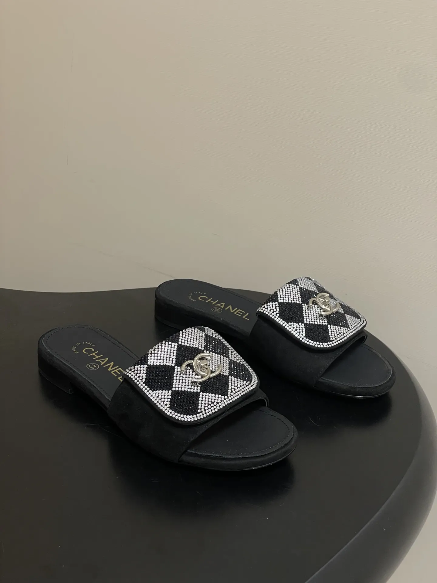 p240- 26Fw春夏新款Chanel小香经典翻盖书包扣水钻一字拖鞋新颖烫钻棋盘格粗跟拖鞋 经典永不过时 简约大气，标志性翻盖双C书包扣设计～手工镶嵌的水钻棋盘轮廓成星河，抬脚时折射出香槟色光晕，显瘦百搭～脚感非常舒适！凸显优雅的爆品 小香粉必入！ 鞋面：羊猄皮/烫钻 内里垫脚：羊皮 高跟：平底/粗跟5cm 鞋底：意大利真皮大底 码数：35-39（40.41.42定做不退换）