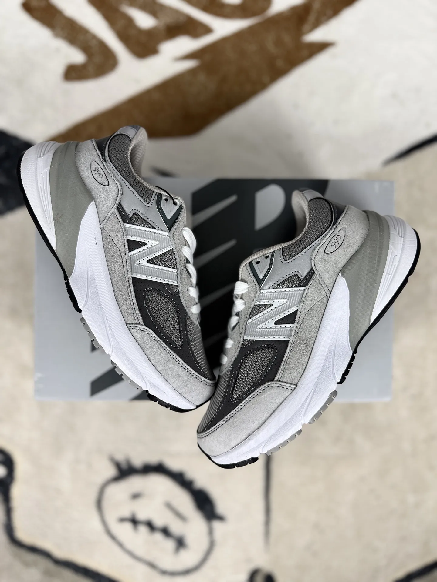 💰180 GS纯原New Balance NB 990 V6 舒适百搭防滑耐磨 低帮跑步鞋 男女款 灰色 新百伦 ▪️NB990V6跑步鞋是一款备受好评的鞋款。鞋面采用绒面革与织物拼接设计，搭配精致的细节点缀，提升了鞋子的质感和触感。这种材质组合不仅舒适耐穿，还赋予了鞋子独特的复古韵味。NB990V6搭载了全新的FuelCell缓震大底，为鞋子提供了出色的缓震性能。这种技术通过氮气注入工艺，使中底回弹性能提升，同时降低了重量，让穿着者在跑步或日常行走中都能感受到柔软而富有弹性的回馈。ENCAP边缘稳定系统有效减少了长距离行走或跑步时的足部疲劳，提供了额外的支撑和稳定性。NB990V6具有一定的增高效果，且穿着稳定，不用担心崴脚问题，鞋子整体设计注重舒适性，无论是日常穿着还是运动场景，都能提供愉悦的穿着体验。采用网眼和穿孔设计，增强了鞋子的透气性，让双脚保持干爽舒适。这款鞋子的设计打破了传统鞋款的性别界限，男女同款设计让它可以轻松适配各种穿搭风格。无论是搭配牛仔裤、休闲裤还是运动装，都能展现出独特的个性。 ▪️尺码：36-45（36 37 37.5 38 38.5 39.5 40 40.5 41.5 42 42.5 43 44 44.5 45） ▪️货号：M990GL6/W990GL6