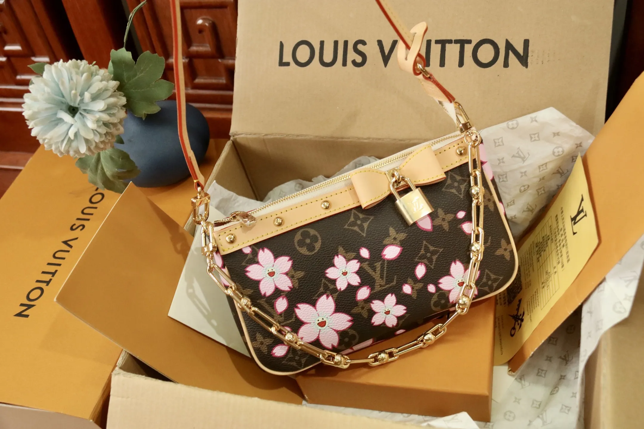 M13666樱花 🌟P350 本款 Pochette Accessoires 手袋为经典 Monogram 帆布融入村上隆笔下的明媚 Cherry Blossom 图案，以玩趣格调道出路易威登 x 村上隆复刻系列的鲜明元素。皮革蝴蝶结与 LV 铭纹挂锁点亮上缘，耀目饰钉与可拆卸链条注入一丝不羁气息。13 x 4 x 22 厘米