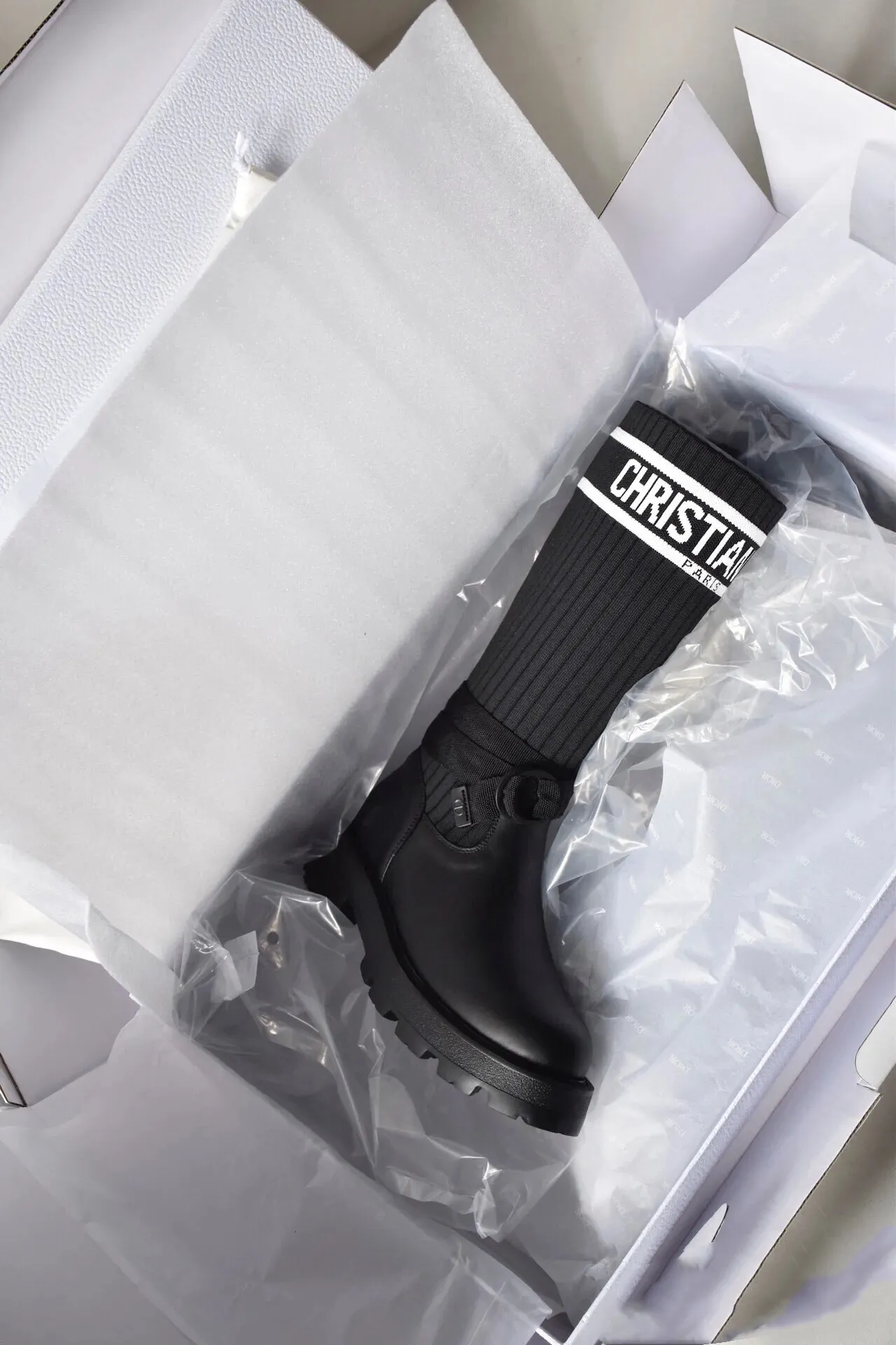 橙子出厂价💰160 Dior 迪奥 弹力袜靴 💫 神仙设计点 ▫️皮革靴头+弹力针织袜筒的碰撞太绝了 靴筒像压力袜一样包裹小腿 却完全不勒肉 皮革部分支撑力超好 走路带风也不变形 ▫️最心机的是袜筒上的白色织带字母 &ldquo;CHRISTIAN DIOR PARIS&rdquo;直接点亮全身 ▫️工装风搭扣+5cm隐形厚底 小个子狂喜 视觉增高10cm不说 还自带复古街头感 💡真实体验： &bull; 针织部分弹性超大 肌肉腿友好 &bull; 厚底走路超稳 逛街暴走无压力 &bull; 织带是立体刺绣的 洗了也不掉色 &bull; 重点是真的显腿直！从脚踝到膝盖的包裹绝了 Size:35-40 现货发售！