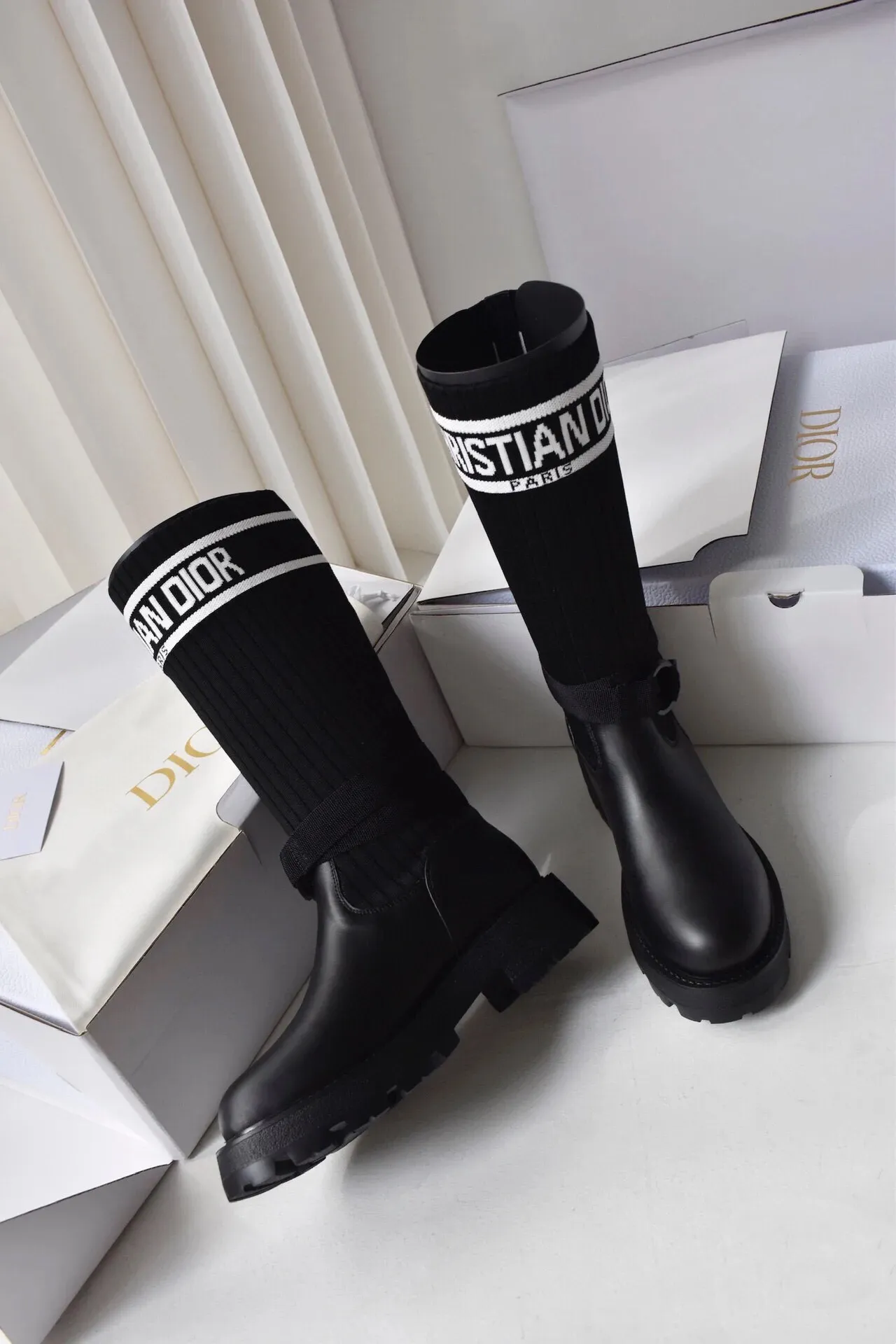 橙子出厂价💰160 Dior 迪奥 弹力袜靴 💫 神仙设计点 ▫️皮革靴头+弹力针织袜筒的碰撞太绝了 靴筒像压力袜一样包裹小腿 却完全不勒肉 皮革部分支撑力超好 走路带风也不变形 ▫️最心机的是袜筒上的白色织带字母 &ldquo;CHRISTIAN DIOR PARIS&rdquo;直接点亮全身 ▫️工装风搭扣+5cm隐形厚底 小个子狂喜 视觉增高10cm不说 还自带复古街头感 💡真实体验： &bull; 针织部分弹性超大 肌肉腿友好 &bull; 厚底走路超稳 逛街暴走无压力 &bull; 织带是立体刺绣的 洗了也不掉色 &bull; 重点是真的显腿直！从脚踝到膝盖的包裹绝了 Size:35-40 现货发售！