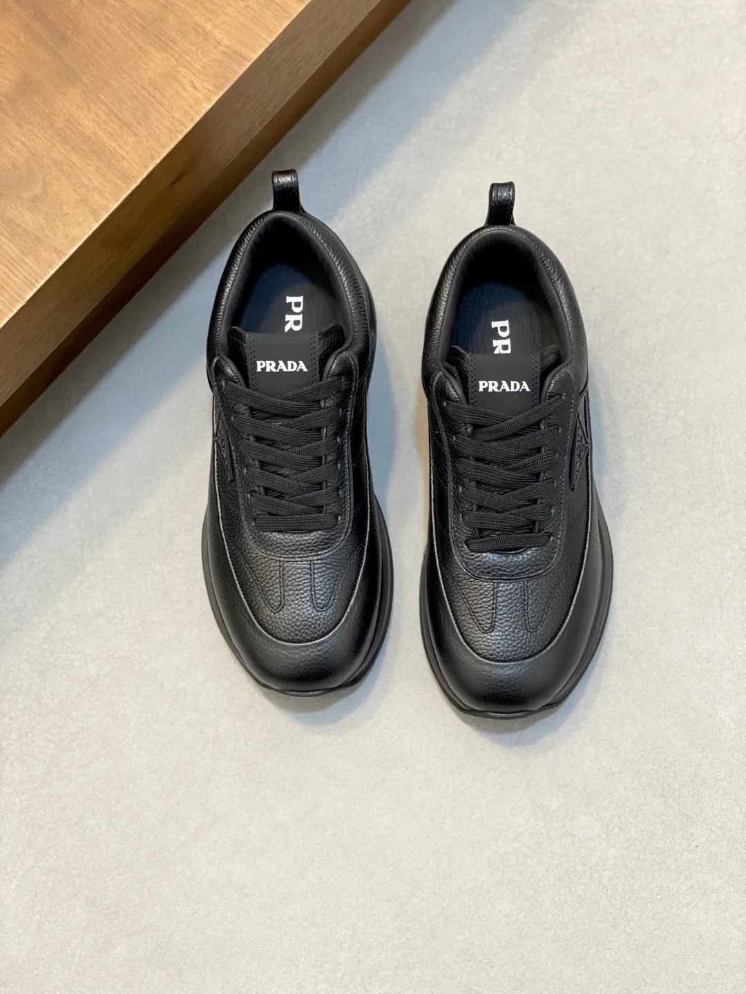 💰390 Prada/普拉达 男士新款皮面拼接运动鞋 这款运动鞋呈现现代版型，以利落线条与流畅细节重新演绎品牌典藏款型。鞋履采用小牛皮革和科技织物打造，外侧饰有三角金属徽标，后跟亮色TPU装饰，内里后跟加长加衬设计，穿着更舒适，鞋舌饰有丝印徽标，搭配后跟镂空橡胶厚底，全牛皮内里标配徽标牛皮垫脚，上脚增高舒适、百搭耐看！配全套原包装！ 码数：39-40-41-42-43-44 标准皮鞋尺码（45可定做不支持退换）