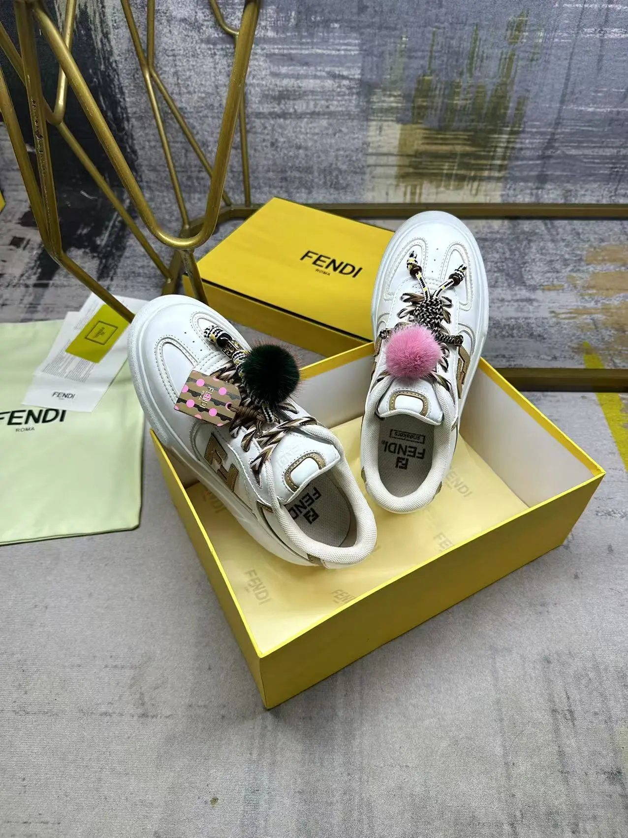 FENDI Match系带运动鞋。白色面料,带米色细节。侧边饰有撞色皮革FF贴花,白色、米色和棕色登山鞋带。橡胶厚鞋底,后跟处饰有超大凸纹压花FENDI字样。鞋舌上饰有金属环挂饰:右鞋上饰有带撞色貂毛细节和金色金属FF图案手链的编绳小玩偶。左鞋上饰有一条带撞色貂毛双绒球的编绳,饰有金属FF圆珠以及Pequin印花图案和标志(玩偶可拆卸),35-42码,P305