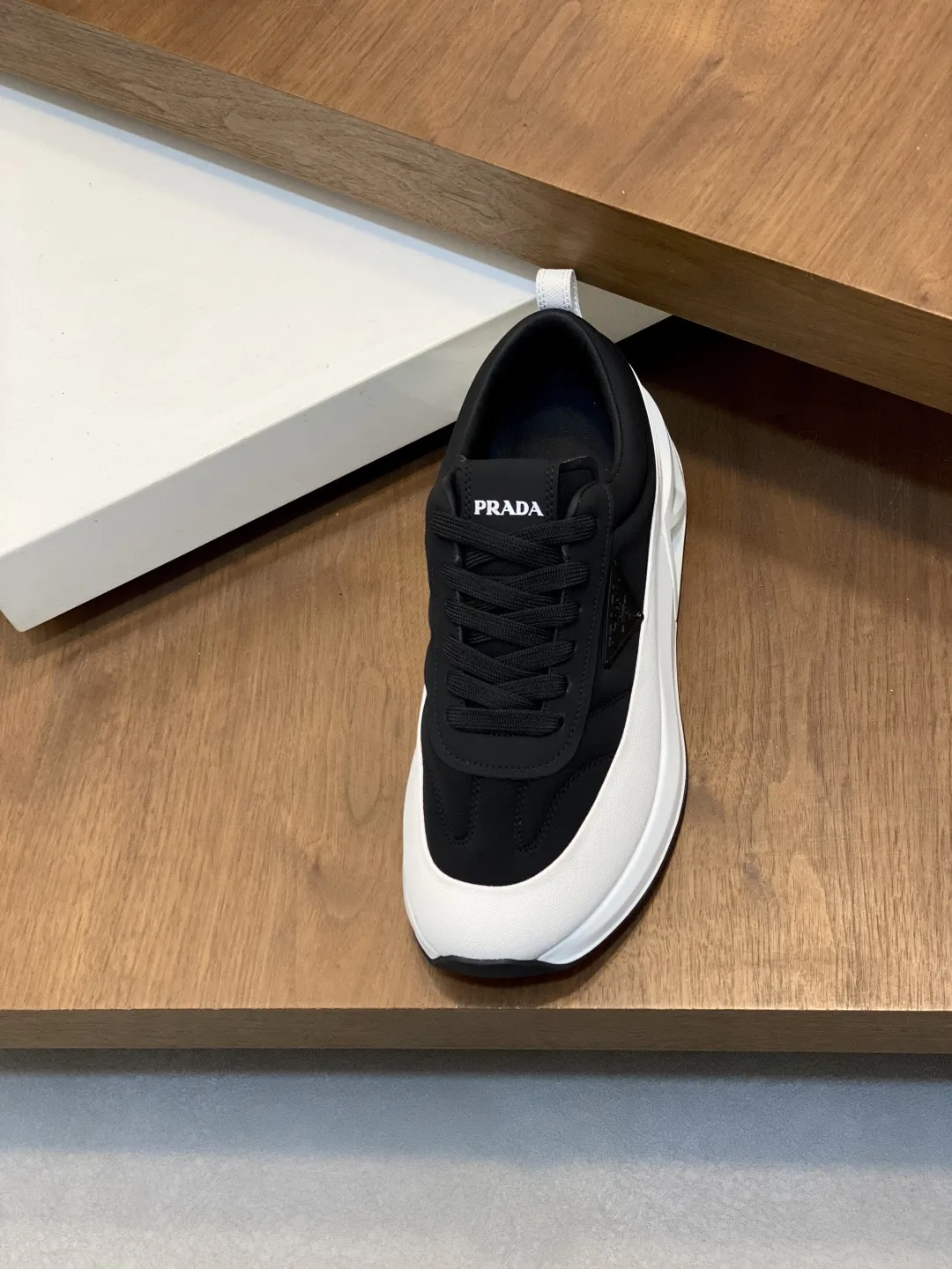 💰380 Prada/普拉达 男士新款皮面拼接运动鞋 这款运动鞋呈现现代版型，以利落线条与流畅细节重新演绎品牌典藏款型。鞋履采用小牛皮革和科技织物打造，外侧饰有三角金属徽标，后跟亮色TPU装饰，内里后跟加长加衬设计，穿着更舒适，鞋舌饰有丝印徽标，搭配后跟镂空橡胶厚底，全牛皮内里标配徽标牛皮垫脚，上脚增高舒适、百搭耐看！配全套原包装！ 码数：39-40-41-42-43-44 标准皮鞋尺码（45可定做不支持退换）