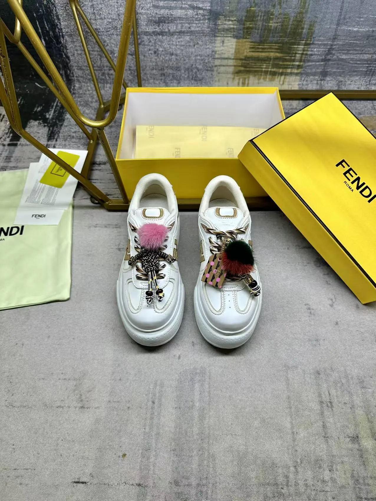 FENDI Match系带运动鞋。白色面料，带米色细节。侧边饰有撞色皮革FF贴花，白色、米色和棕色登山鞋带。橡胶厚鞋底，后跟处饰有超大凸纹压花FENDI字样。鞋舌上饰有金属环挂饰：右鞋上饰有带撞色貂毛细节和金色金属FF图案手链的编绳小玩偶。左鞋上饰有一条带撞色貂毛双绒球的编绳，饰有金属FF圆珠以及Pequin印花图案和标志（玩偶可拆卸），35-42码，P305