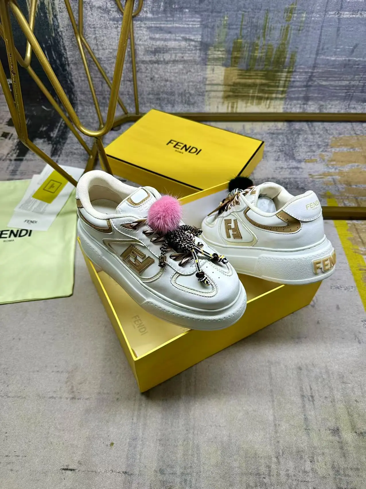 FENDI Match系带运动鞋。白色面料,带米色细节。侧边饰有撞色皮革FF贴花,白色、米色和棕色登山鞋带。橡胶厚鞋底,后跟处饰有超大凸纹压花FENDI字样。鞋舌上饰有金属环挂饰:右鞋上饰有带撞色貂毛细节和金色金属FF图案手链的编绳小玩偶。左鞋上饰有一条带撞色貂毛双绒球的编绳,饰有金属FF圆珠以及Pequin印花图案和标志(玩偶可拆卸),35-42码,P305