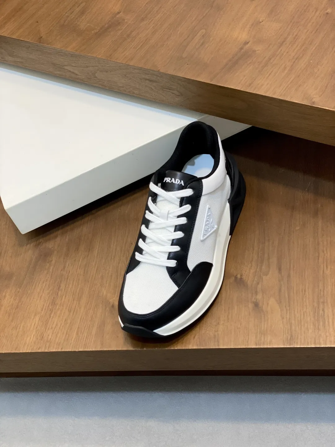 💰360 Prada/普拉达 男士新款网面拼接运动鞋 这款运动鞋呈现现代版型，以利落线条与流畅细节重新演绎品牌典藏款型。鞋履采用小牛皮革和科技织物打造，外侧饰有三角金属徽标，后跟亮色TPU装饰，内里后跟加长加衬设计，穿着更舒适，鞋舌饰有丝印徽标，搭配后跟镂空橡胶厚底，全牛皮内里标配徽标牛皮垫脚，上脚增高舒适、百搭耐看！配全套原包装！ 码数：39-40-41-42-43-44 标准皮鞋尺码（45可定做不支持退换）