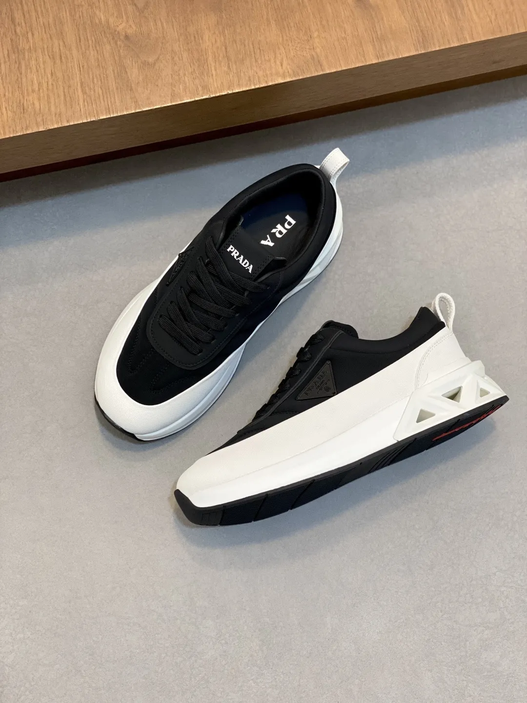 💰380 Prada/普拉达 男士新款皮面拼接运动鞋 这款运动鞋呈现现代版型，以利落线条与流畅细节重新演绎品牌典藏款型。鞋履采用小牛皮革和科技织物打造，外侧饰有三角金属徽标，后跟亮色TPU装饰，内里后跟加长加衬设计，穿着更舒适，鞋舌饰有丝印徽标，搭配后跟镂空橡胶厚底，全牛皮内里标配徽标牛皮垫脚，上脚增高舒适、百搭耐看！配全套原包装！ 码数：39-40-41-42-43-44 标准皮鞋尺码（45可定做不支持退换）