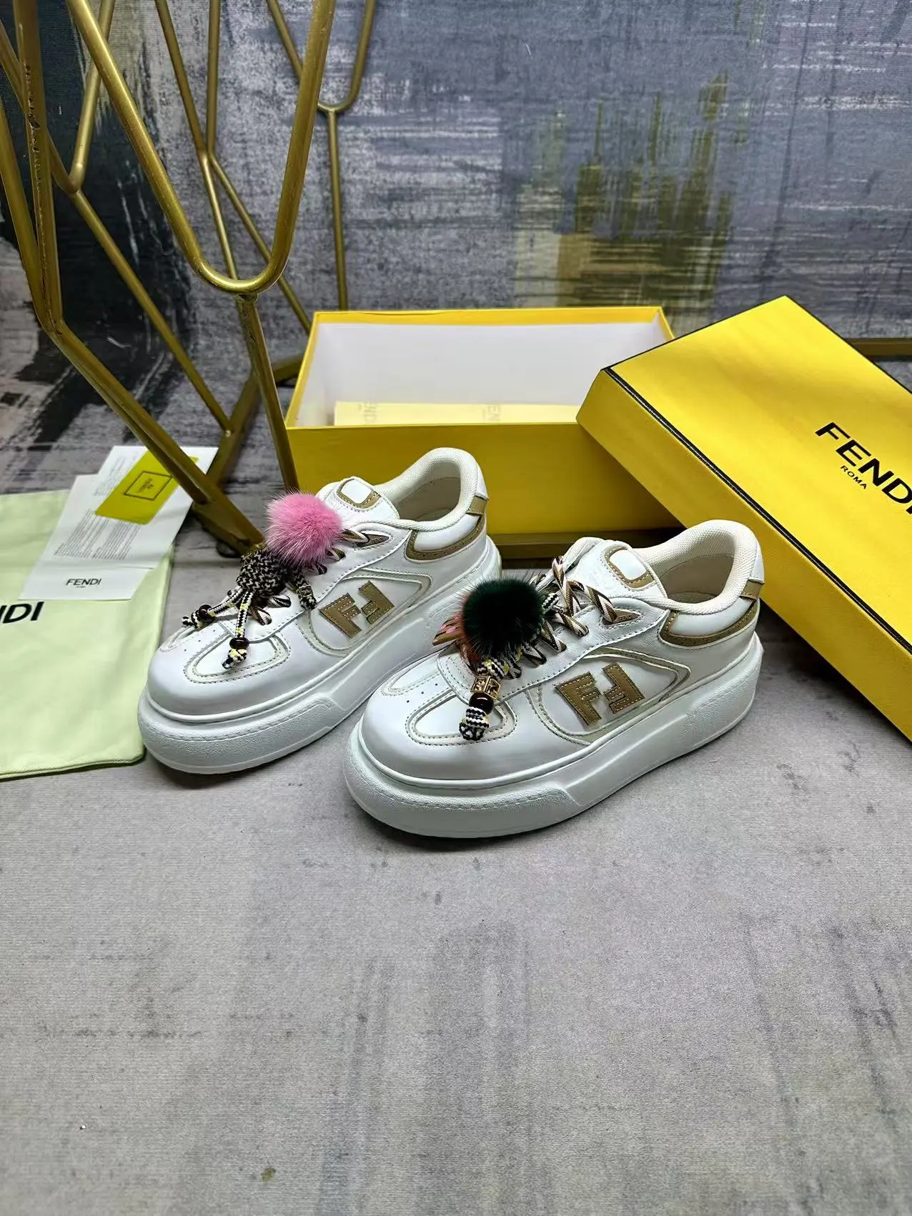 FENDI Match系带运动鞋。白色面料,带米色细节。侧边饰有撞色皮革FF贴花,白色、米色和棕色登山鞋带。橡胶厚鞋底,后跟处饰有超大凸纹压花FENDI字样。鞋舌上饰有金属环挂饰:右鞋上饰有带撞色貂毛细节和金色金属FF图案手链的编绳小玩偶。左鞋上饰有一条带撞色貂毛双绒球的编绳,饰有金属FF圆珠以及Pequin印花图案和标志(玩偶可拆卸),35-42码,P305