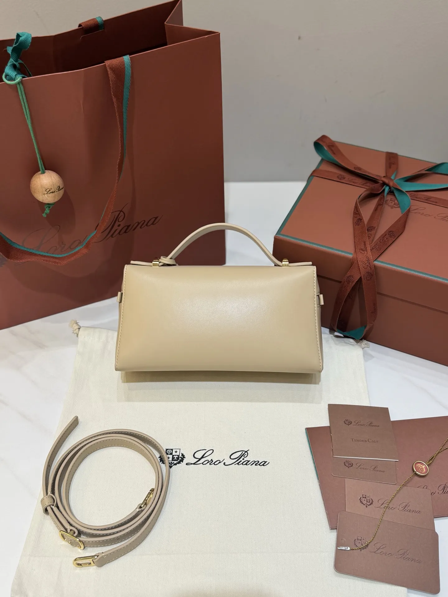 💰600 Extra Bag23手袋【平纹浅乳香】 采用Saddle Leather牛皮革材质精心制作,饰以繁复精致的明迹缝线,既可手提,亦可斜挎。双拉链开合处悬挂着LoroPiana的标志性挂饰,并搭配精致的皮革钥匙扣,可拆卸可调节肩带 双向拉链开合,饰有挂饰 内部皮革卡槽 皮革钥匙扣 绒面革衬里 金属色配件尺寸:23x12x 厘米手柄高度:5厘米 肩带长度:46-58厘米