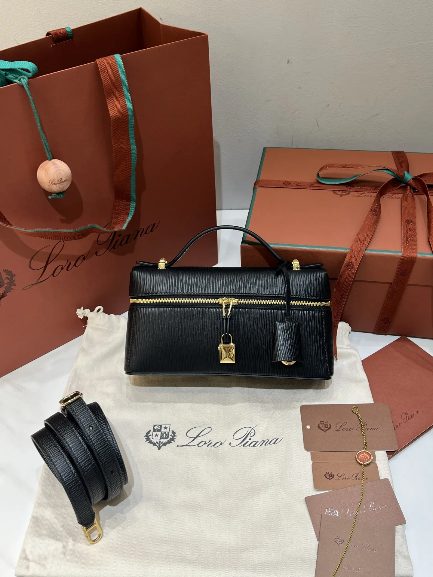 💰600 Extra Bag23手袋【水波纹黑色】 采用Saddle Leather牛皮革材质精心制作，饰以繁复精致的明迹缝线，既可手提，亦可斜挎。双拉链开合处悬挂着LoroPiana的标志性挂饰，并搭配精致的皮革钥匙扣，可拆卸可调节肩带 双向拉链开合，饰有挂饰 内部皮革卡槽 皮革钥匙扣 绒面革衬里 金属色配件尺寸：23x12x 厘米手柄高度：5厘米 肩带长度：46-58厘米