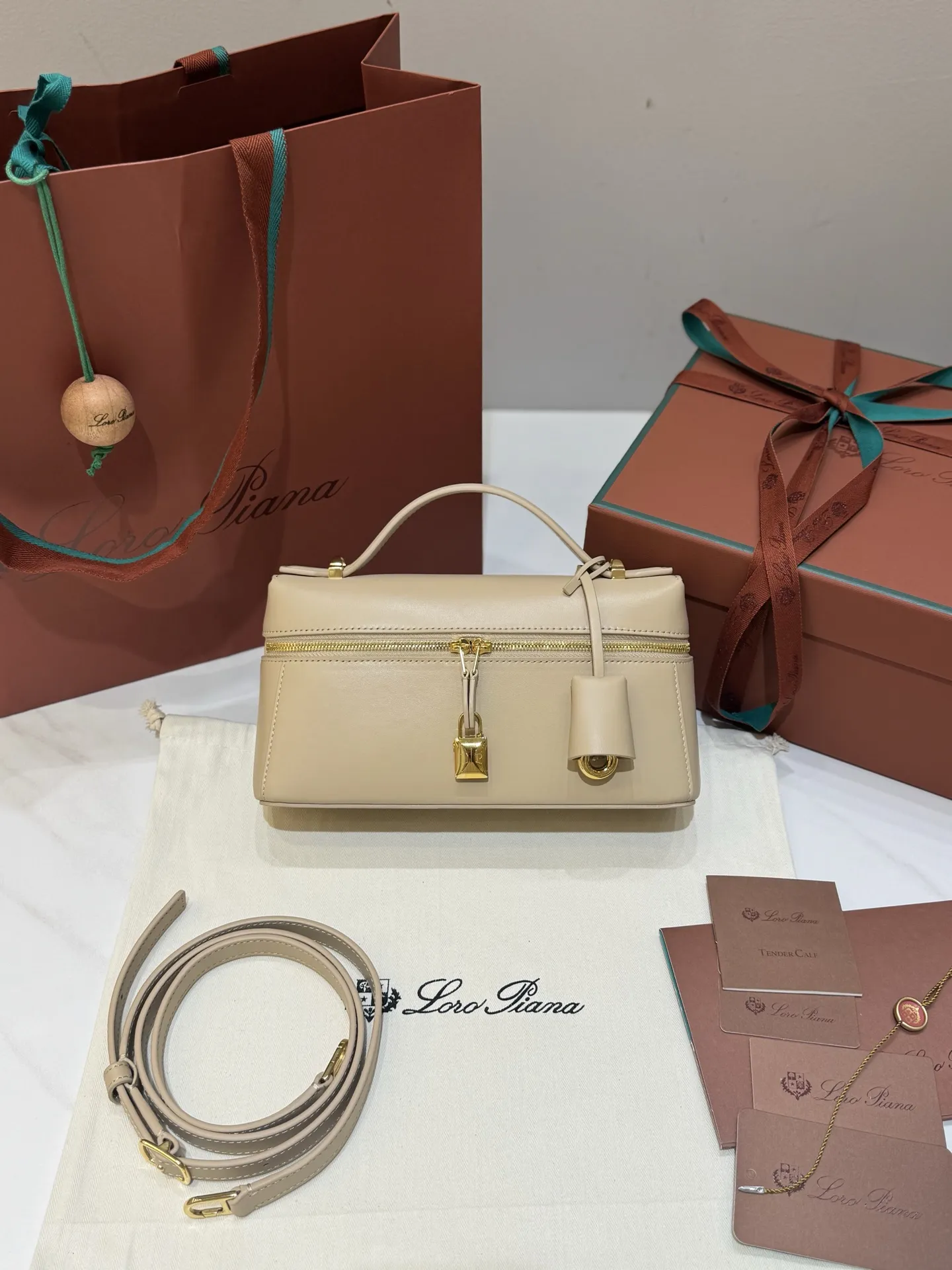 💰600 Extra Bag23手袋【平纹浅乳香】 采用Saddle Leather牛皮革材质精心制作，饰以繁复精致的明迹缝线，既可手提，亦可斜挎。双拉链开合处悬挂着LoroPiana的标志性挂饰，并搭配精致的皮革钥匙扣，可拆卸可调节肩带 双向拉链开合，饰有挂饰 内部皮革卡槽 皮革钥匙扣 绒面革衬里 金属色配件尺寸：23x12x 厘米手柄高度：5厘米 肩带长度：46-58厘米