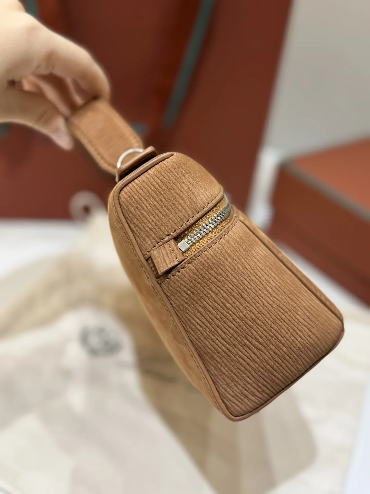 💰600 Extra Bag23手袋【天鹅绒水波纹暖棕褐色】 采用Saddle Leather牛皮革材质精心制作,饰以繁复精致的明迹缝线,既可手提,亦可斜挎。双拉链开合处悬挂着LoroPiana的标志性挂饰,并搭配精致的皮革钥匙扣,可拆卸可调节肩带 双向拉链开合,饰有挂饰 内部皮革卡槽 皮革钥匙扣 绒面革衬里 金属色配件尺寸:23x12x 厘米手柄高度:5厘米 肩带长度:46-58厘米