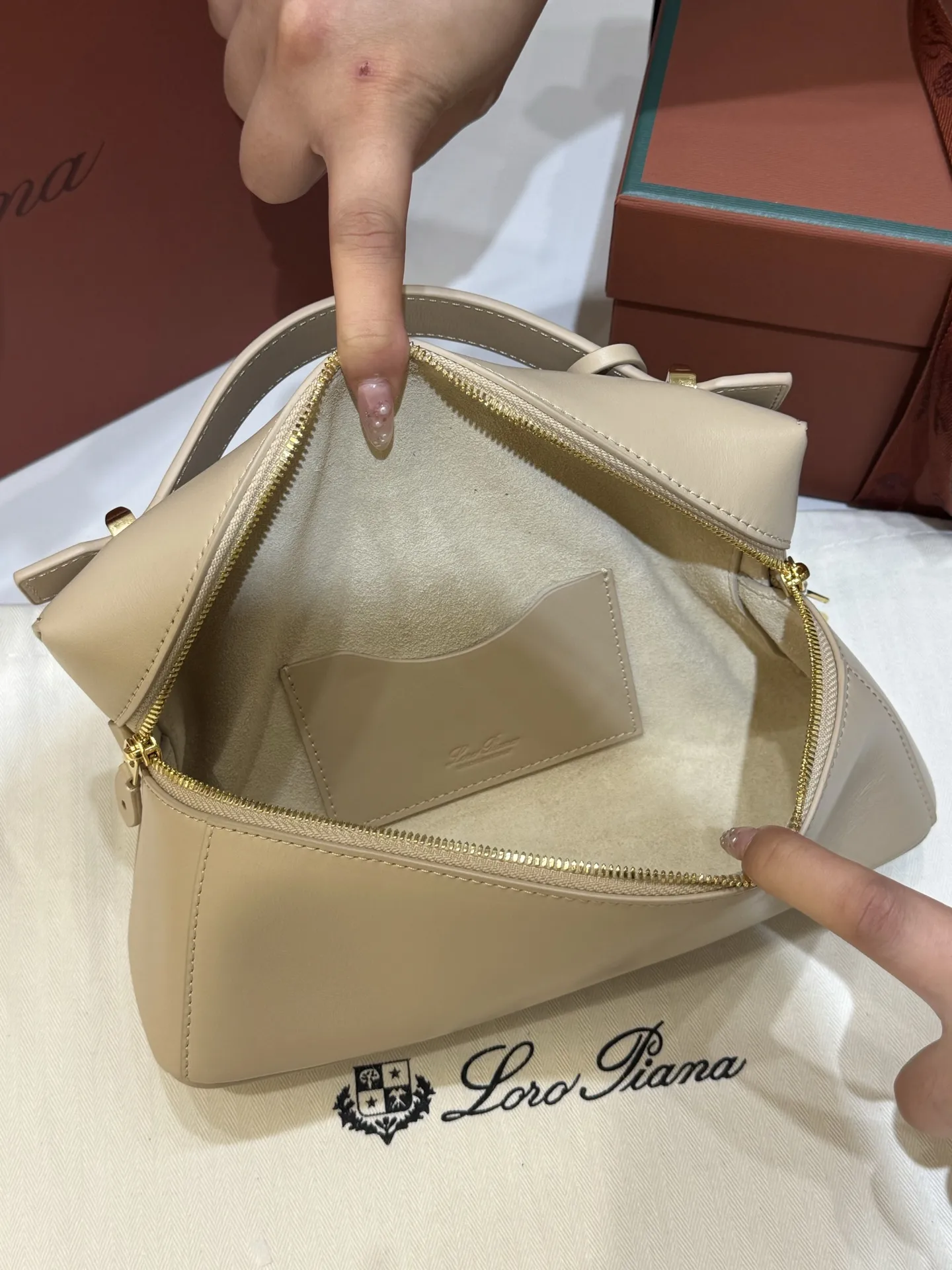 💰600 Extra Bag23手袋【平纹浅乳香】 采用Saddle Leather牛皮革材质精心制作，饰以繁复精致的明迹缝线，既可手提，亦可斜挎。双拉链开合处悬挂着LoroPiana的标志性挂饰，并搭配精致的皮革钥匙扣，可拆卸可调节肩带 双向拉链开合，饰有挂饰 内部皮革卡槽 皮革钥匙扣 绒面革衬里 金属色配件尺寸：23x12x 厘米手柄高度：5厘米 肩带长度：46-58厘米