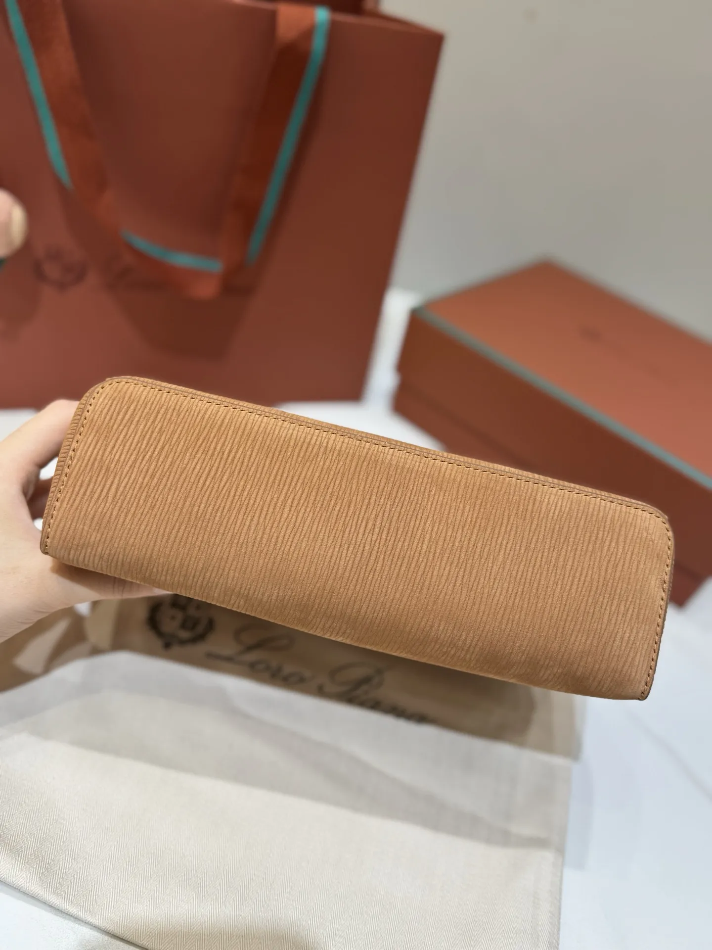 💰600 Extra Bag23手袋【天鹅绒水波纹暖棕褐色】 采用Saddle Leather牛皮革材质精心制作,饰以繁复精致的明迹缝线,既可手提,亦可斜挎。双拉链开合处悬挂着LoroPiana的标志性挂饰,并搭配精致的皮革钥匙扣,可拆卸可调节肩带 双向拉链开合,饰有挂饰 内部皮革卡槽 皮革钥匙扣 绒面革衬里 金属色配件尺寸:23x12x 厘米手柄高度:5厘米 肩带长度:46-58厘米