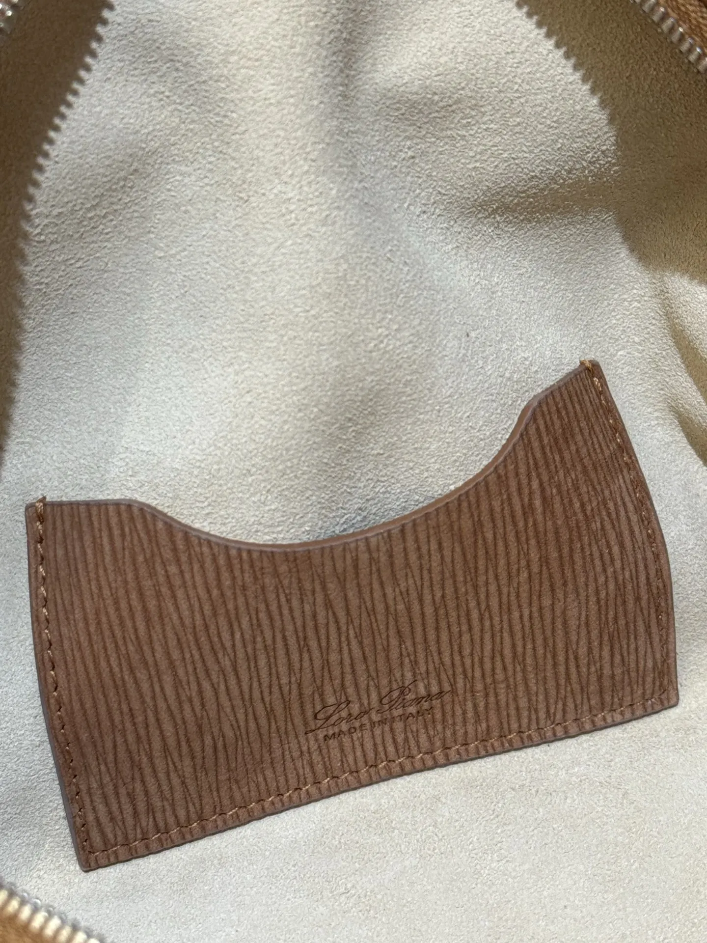 💰600 Extra Bag23手袋【天鹅绒水波纹暖棕褐色】 采用Saddle Leather牛皮革材质精心制作,饰以繁复精致的明迹缝线,既可手提,亦可斜挎。双拉链开合处悬挂着LoroPiana的标志性挂饰,并搭配精致的皮革钥匙扣,可拆卸可调节肩带 双向拉链开合,饰有挂饰 内部皮革卡槽 皮革钥匙扣 绒面革衬里 金属色配件尺寸:23x12x 厘米手柄高度:5厘米 肩带长度:46-58厘米