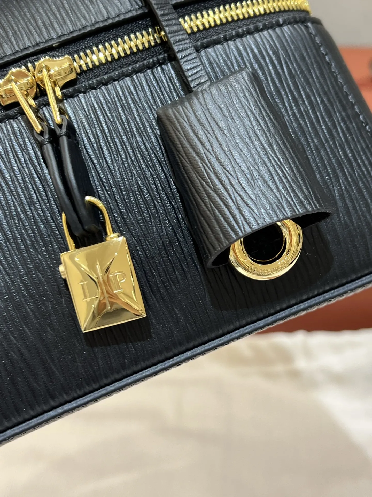 💰600 Extra Bag23手袋【水波纹黑色】 采用Saddle Leather牛皮革材质精心制作,饰以繁复精致的明迹缝线,既可手提,亦可斜挎。双拉链开合处悬挂着LoroPiana的标志性挂饰,并搭配精致的皮革钥匙扣,可拆卸可调节肩带 双向拉链开合,饰有挂饰 内部皮革卡槽 皮革钥匙扣 绒面革衬里 金属色配件尺寸:23x12x 厘米手柄高度:5厘米 肩带长度:46-58厘米