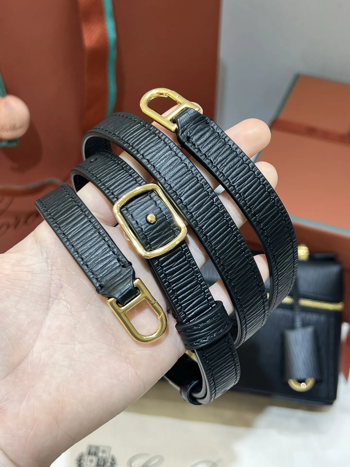 💰600 Extra Bag23手袋【水波纹黑色】 采用Saddle Leather牛皮革材质精心制作，饰以繁复精致的明迹缝线，既可手提，亦可斜挎。双拉链开合处悬挂着LoroPiana的标志性挂饰，并搭配精致的皮革钥匙扣，可拆卸可调节肩带 双向拉链开合，饰有挂饰 内部皮革卡槽 皮革钥匙扣 绒面革衬里 金属色配件尺寸：23x12x 厘米手柄高度：5厘米 肩带长度：46-58厘米