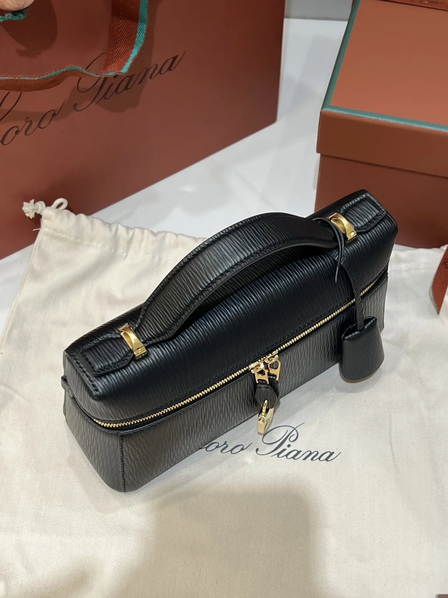 💰600 Extra Bag23手袋【水波纹黑色】 采用Saddle Leather牛皮革材质精心制作，饰以繁复精致的明迹缝线，既可手提，亦可斜挎。双拉链开合处悬挂着LoroPiana的标志性挂饰，并搭配精致的皮革钥匙扣，可拆卸可调节肩带 双向拉链开合，饰有挂饰 内部皮革卡槽 皮革钥匙扣 绒面革衬里 金属色配件尺寸：23x12x 厘米手柄高度：5厘米 肩带长度：46-58厘米