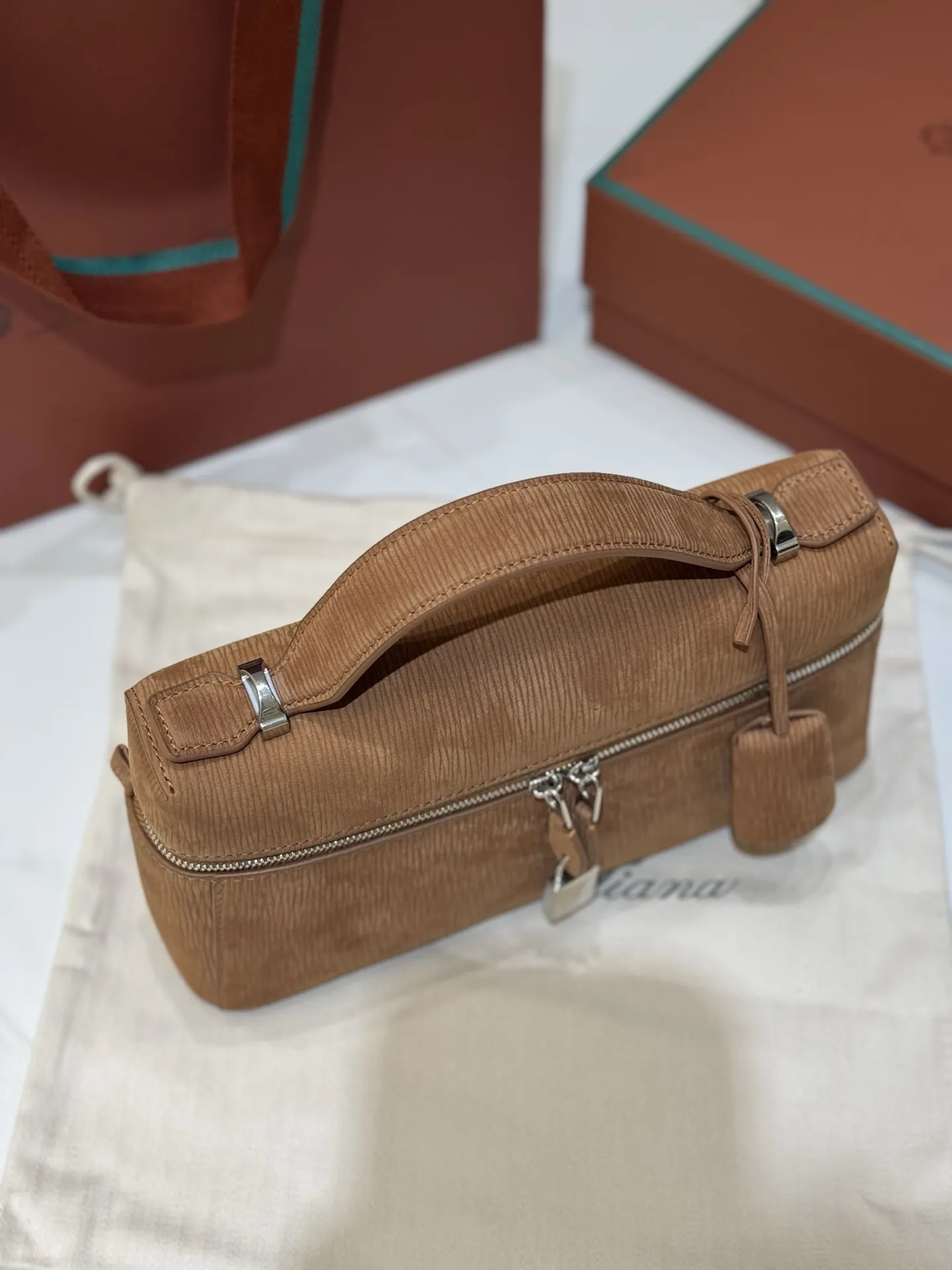 💰600 Extra Bag23手袋【天鹅绒水波纹暖棕褐色】 采用Saddle Leather牛皮革材质精心制作，饰以繁复精致的明迹缝线，既可手提，亦可斜挎。双拉链开合处悬挂着LoroPiana的标志性挂饰，并搭配精致的皮革钥匙扣，可拆卸可调节肩带 双向拉链开合，饰有挂饰 内部皮革卡槽 皮革钥匙扣 绒面革衬里 金属色配件尺寸：23x12x 厘米手柄高度：5厘米 肩带长度：46-58厘米