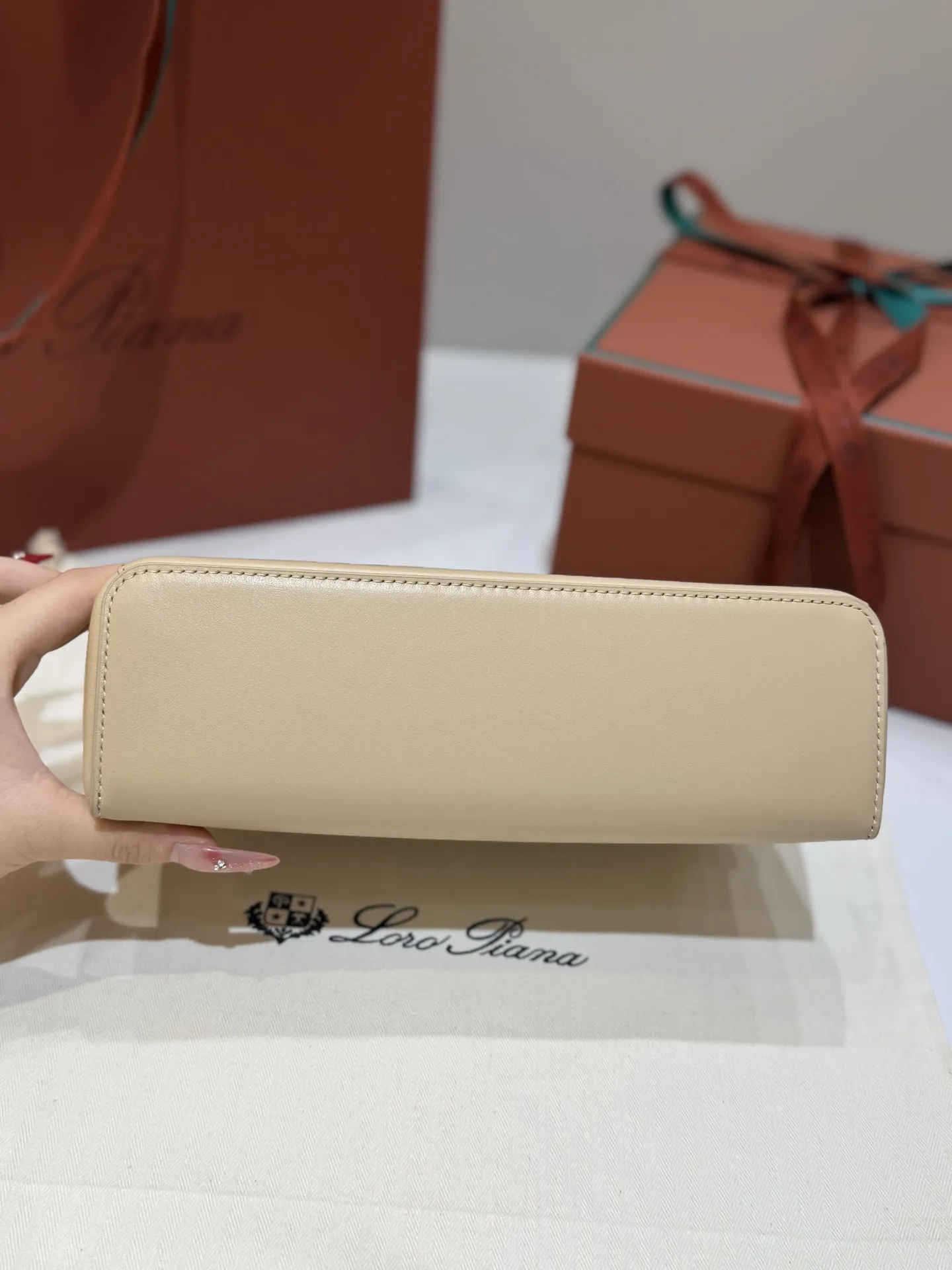 💰600 Extra Bag23手袋【平纹浅乳香】 采用Saddle Leather牛皮革材质精心制作,饰以繁复精致的明迹缝线,既可手提,亦可斜挎。双拉链开合处悬挂着LoroPiana的标志性挂饰,并搭配精致的皮革钥匙扣,可拆卸可调节肩带 双向拉链开合,饰有挂饰 内部皮革卡槽 皮革钥匙扣 绒面革衬里 金属色配件尺寸:23x12x 厘米手柄高度:5厘米 肩带长度:46-58厘米