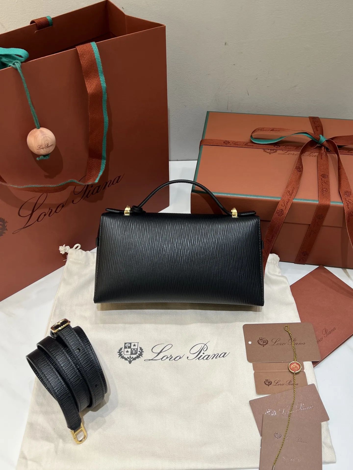 💰600 Extra Bag23手袋【水波纹黑色】 采用Saddle Leather牛皮革材质精心制作，饰以繁复精致的明迹缝线，既可手提，亦可斜挎。双拉链开合处悬挂着LoroPiana的标志性挂饰，并搭配精致的皮革钥匙扣，可拆卸可调节肩带 双向拉链开合，饰有挂饰 内部皮革卡槽 皮革钥匙扣 绒面革衬里 金属色配件尺寸：23x12x 厘米手柄高度：5厘米 肩带长度：46-58厘米