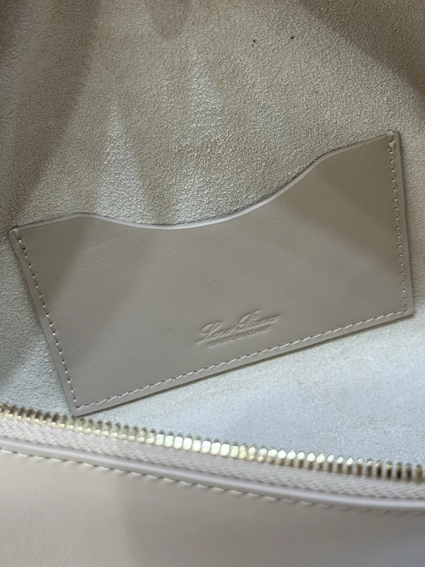 💰600 Extra Bag23手袋【平纹浅乳香】 采用Saddle Leather牛皮革材质精心制作,饰以繁复精致的明迹缝线,既可手提,亦可斜挎。双拉链开合处悬挂着LoroPiana的标志性挂饰,并搭配精致的皮革钥匙扣,可拆卸可调节肩带 双向拉链开合,饰有挂饰 内部皮革卡槽 皮革钥匙扣 绒面革衬里 金属色配件尺寸:23x12x 厘米手柄高度:5厘米 肩带长度:46-58厘米