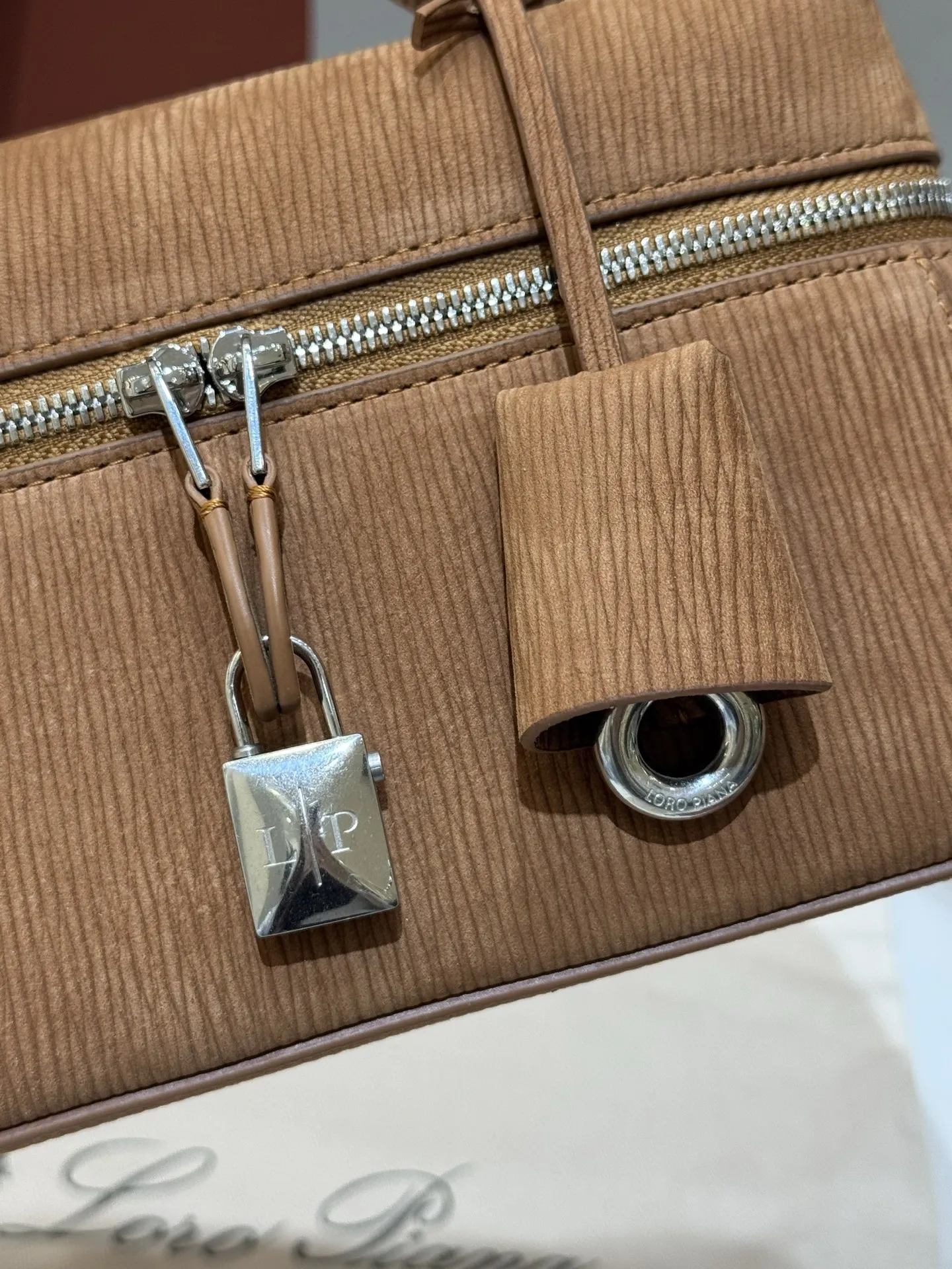 💰600 Extra Bag23手袋【天鹅绒水波纹暖棕褐色】 采用Saddle Leather牛皮革材质精心制作,饰以繁复精致的明迹缝线,既可手提,亦可斜挎。双拉链开合处悬挂着LoroPiana的标志性挂饰,并搭配精致的皮革钥匙扣,可拆卸可调节肩带 双向拉链开合,饰有挂饰 内部皮革卡槽 皮革钥匙扣 绒面革衬里 金属色配件尺寸:23x12x 厘米手柄高度:5厘米 肩带长度:46-58厘米