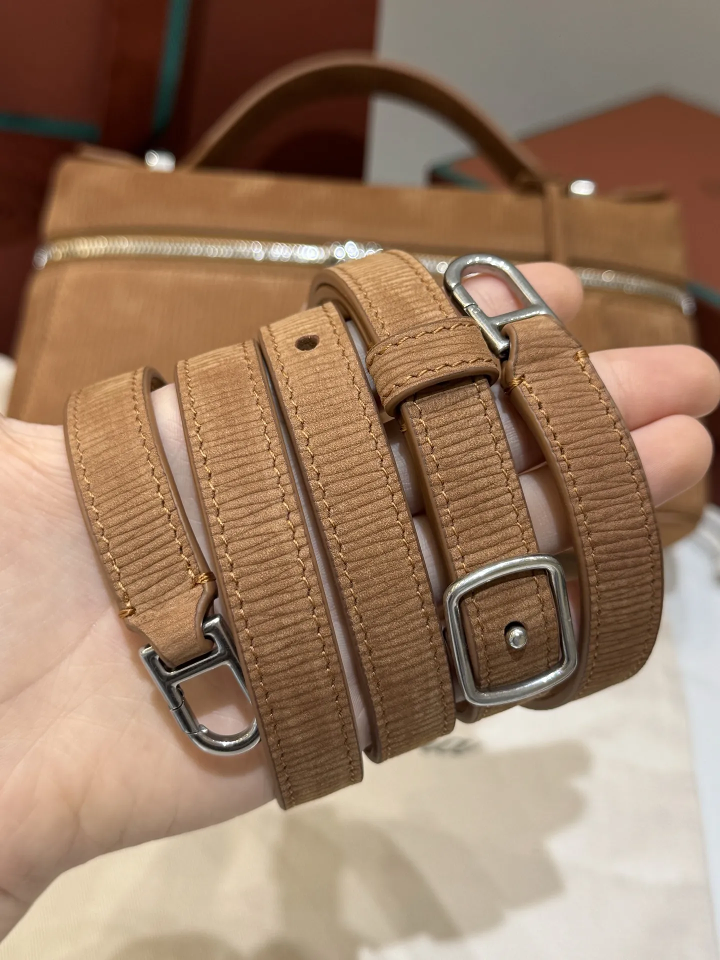 💰600 Extra Bag23手袋【天鹅绒水波纹暖棕褐色】 采用Saddle Leather牛皮革材质精心制作,饰以繁复精致的明迹缝线,既可手提,亦可斜挎。双拉链开合处悬挂着LoroPiana的标志性挂饰,并搭配精致的皮革钥匙扣,可拆卸可调节肩带 双向拉链开合,饰有挂饰 内部皮革卡槽 皮革钥匙扣 绒面革衬里 金属色配件尺寸:23x12x 厘米手柄高度:5厘米 肩带长度:46-58厘米