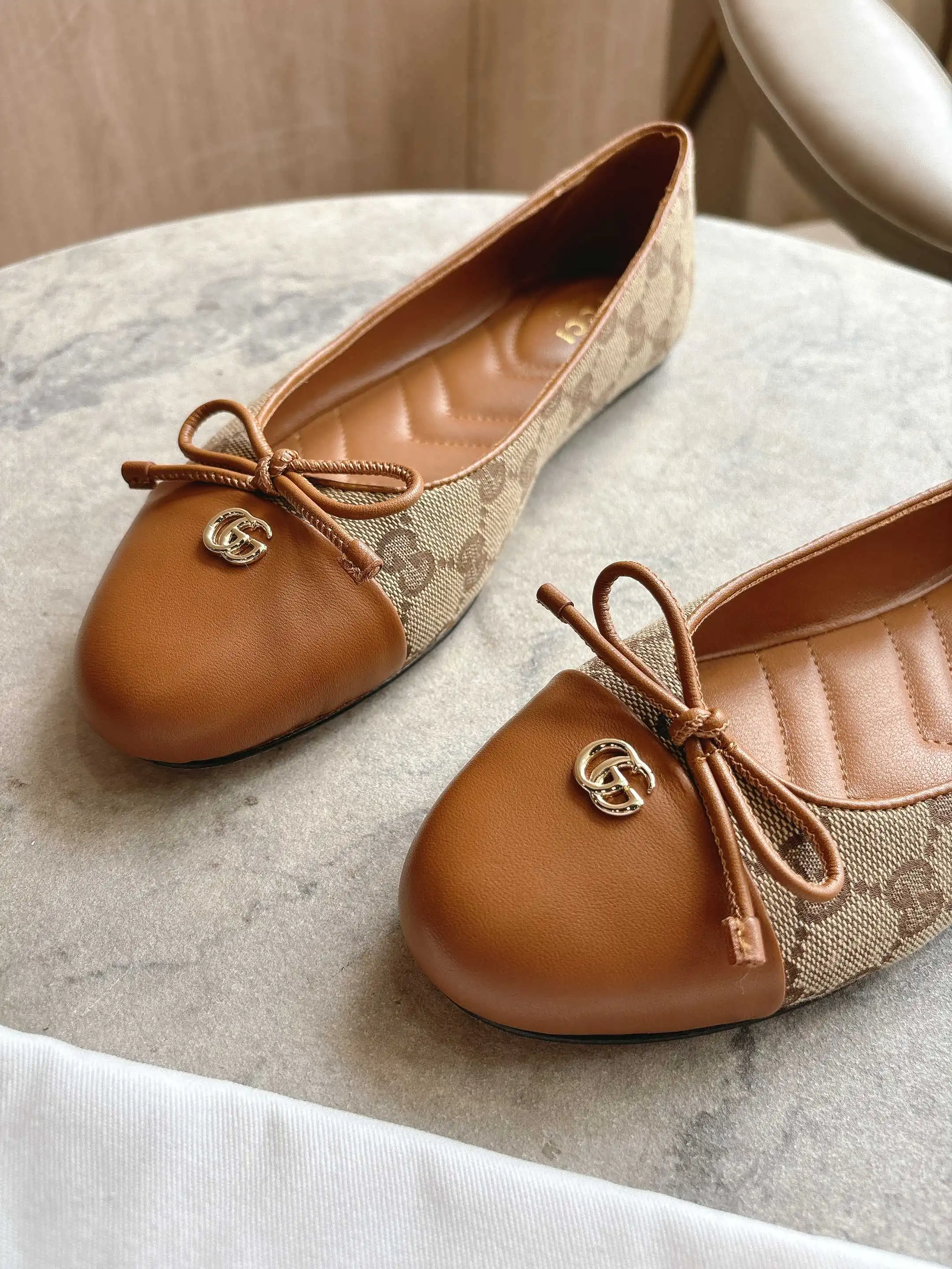 1054-1 杏G&yen;270（35-42）这款平底芭蕾舞鞋选用皮革制作，尽显优雅隽永格调。精巧蝴蝶结流露女性气质，浅金色调双G配件低调呼应品牌高辨识度标识。 杏色皮革 浅金色调配件 绗缝皮革内底 蝴蝶结和双G 皮革鞋底 平底