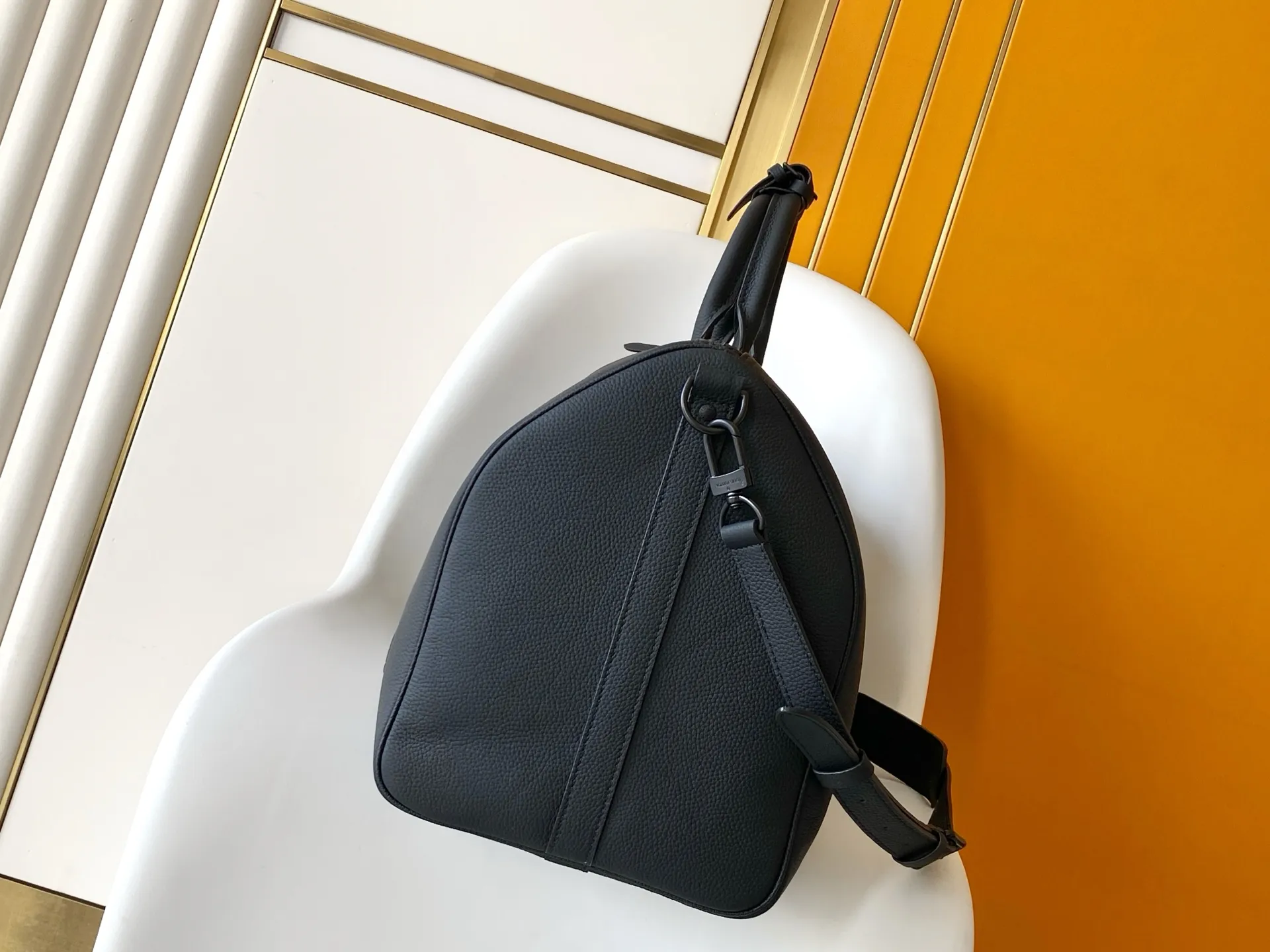 Louis Vuitton Keepall Bandoulière 1:1 Aerogram black leather travel bag on a white chair - xiashuluxe