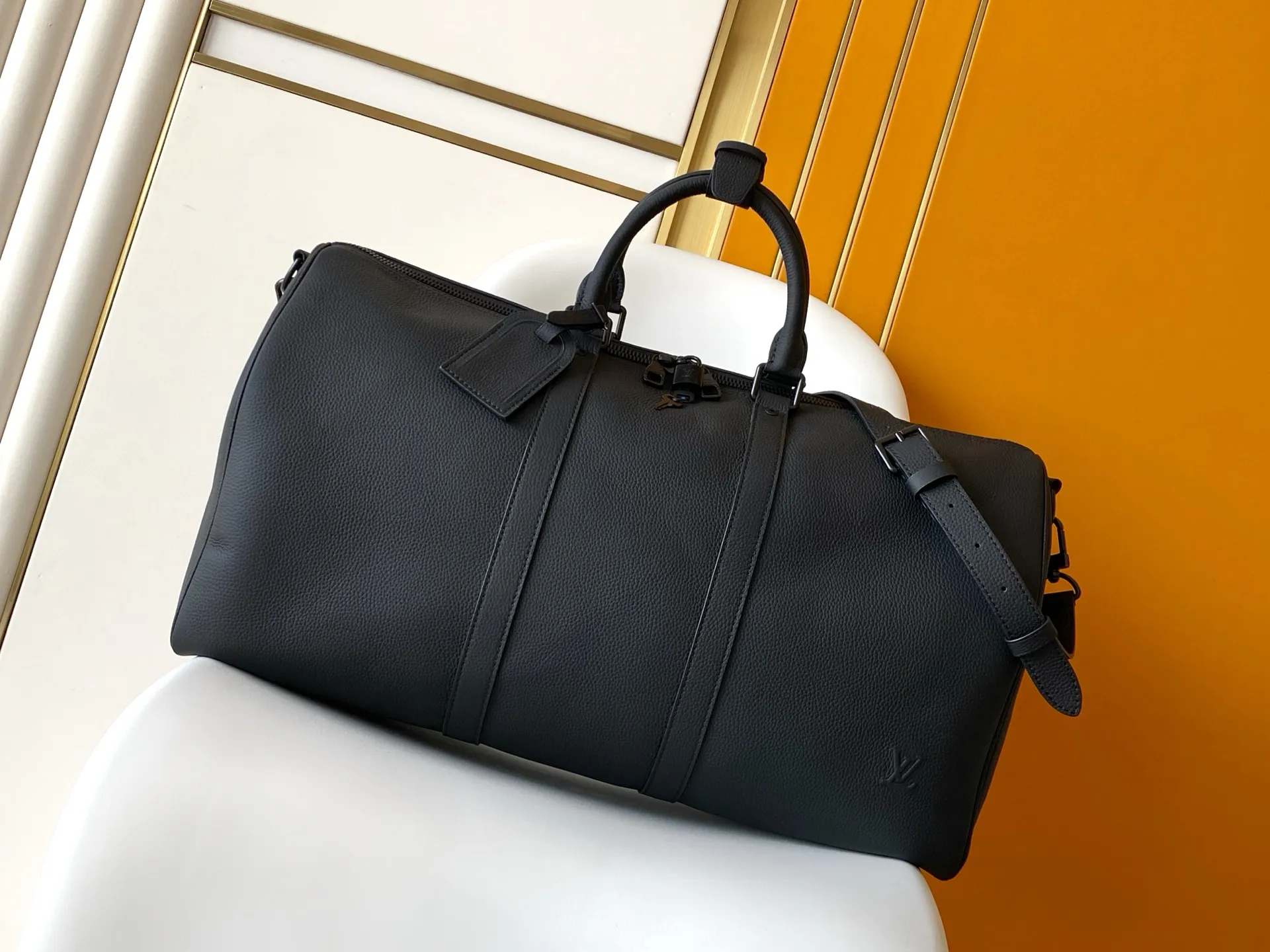 Louis Vuitton Keepall Bandouli&egrave;re 1:1 Aerogram black leather travel bag on a white chair - xiashuluxe